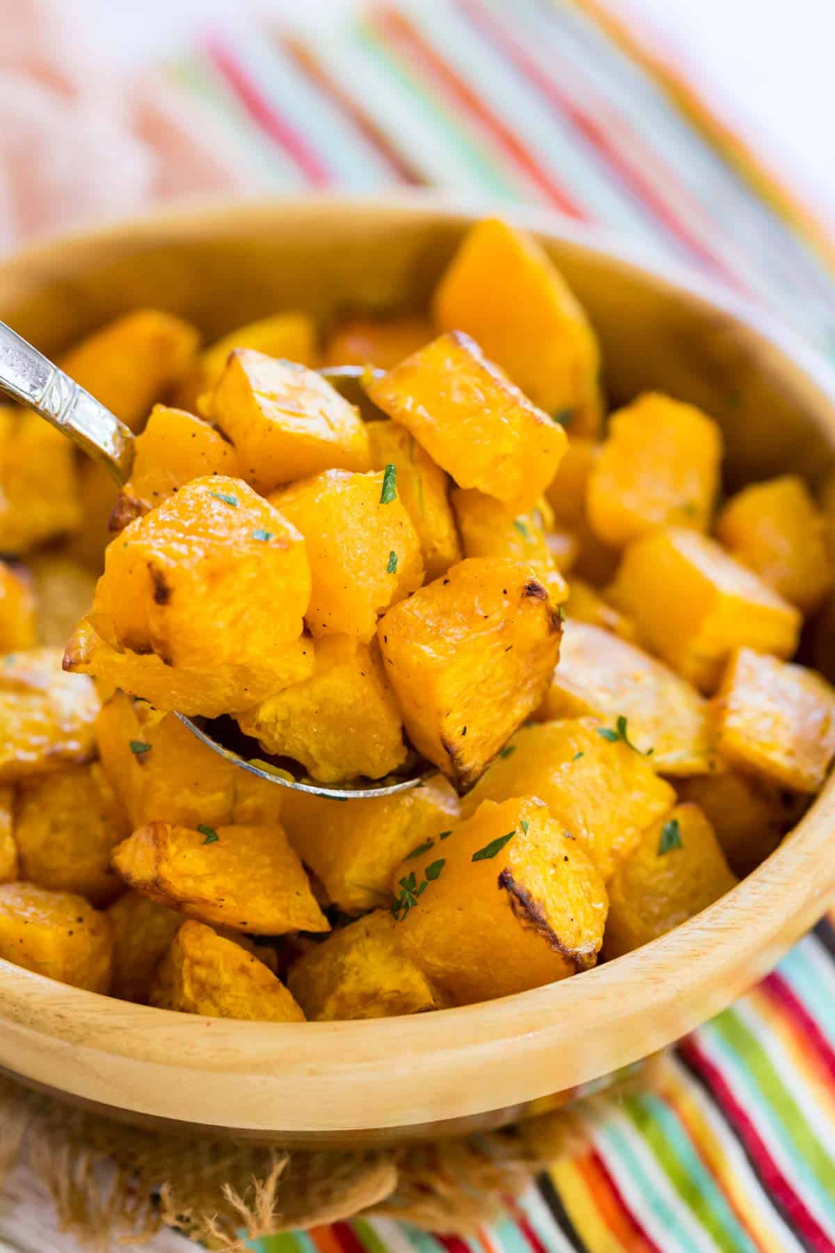 A spoon lifts a serving of air fryer butternut squash from a bowl.