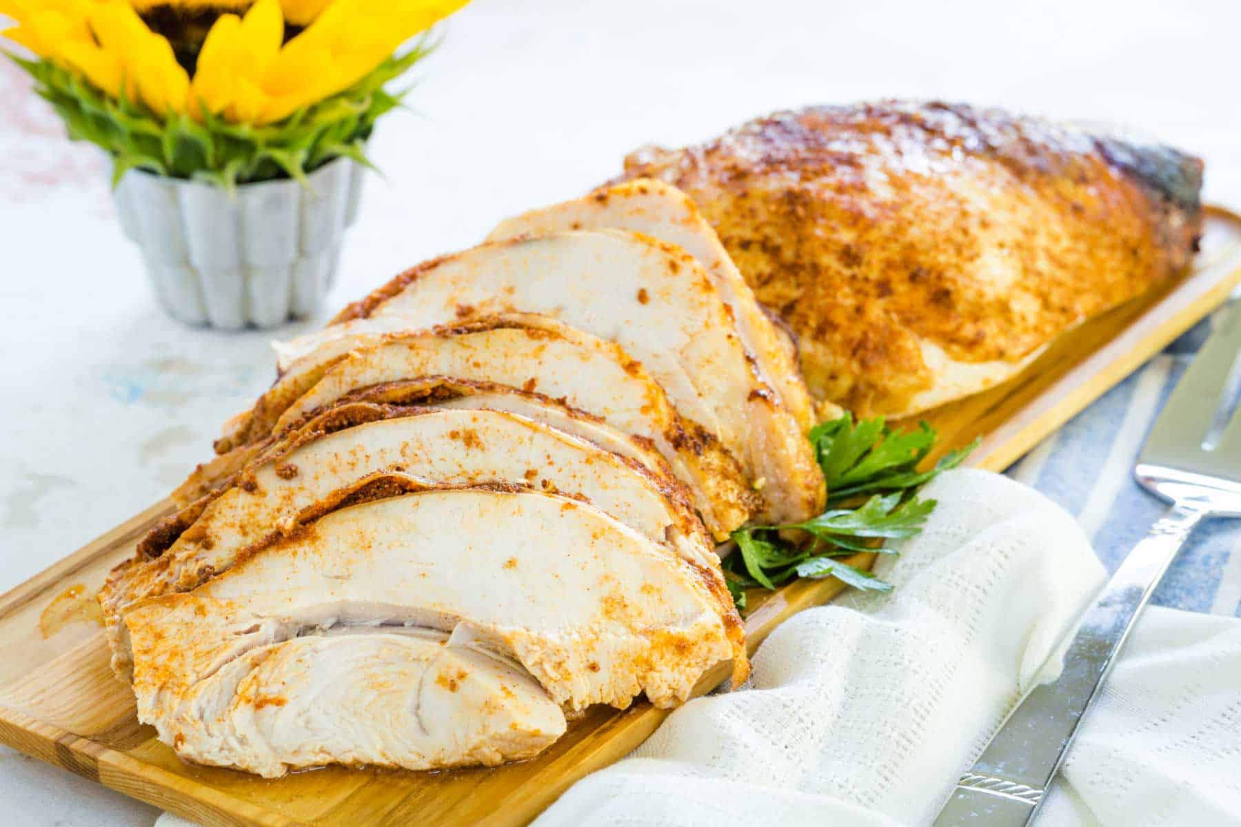 A sliced turkey breast coated with seasoning on a cutting board.