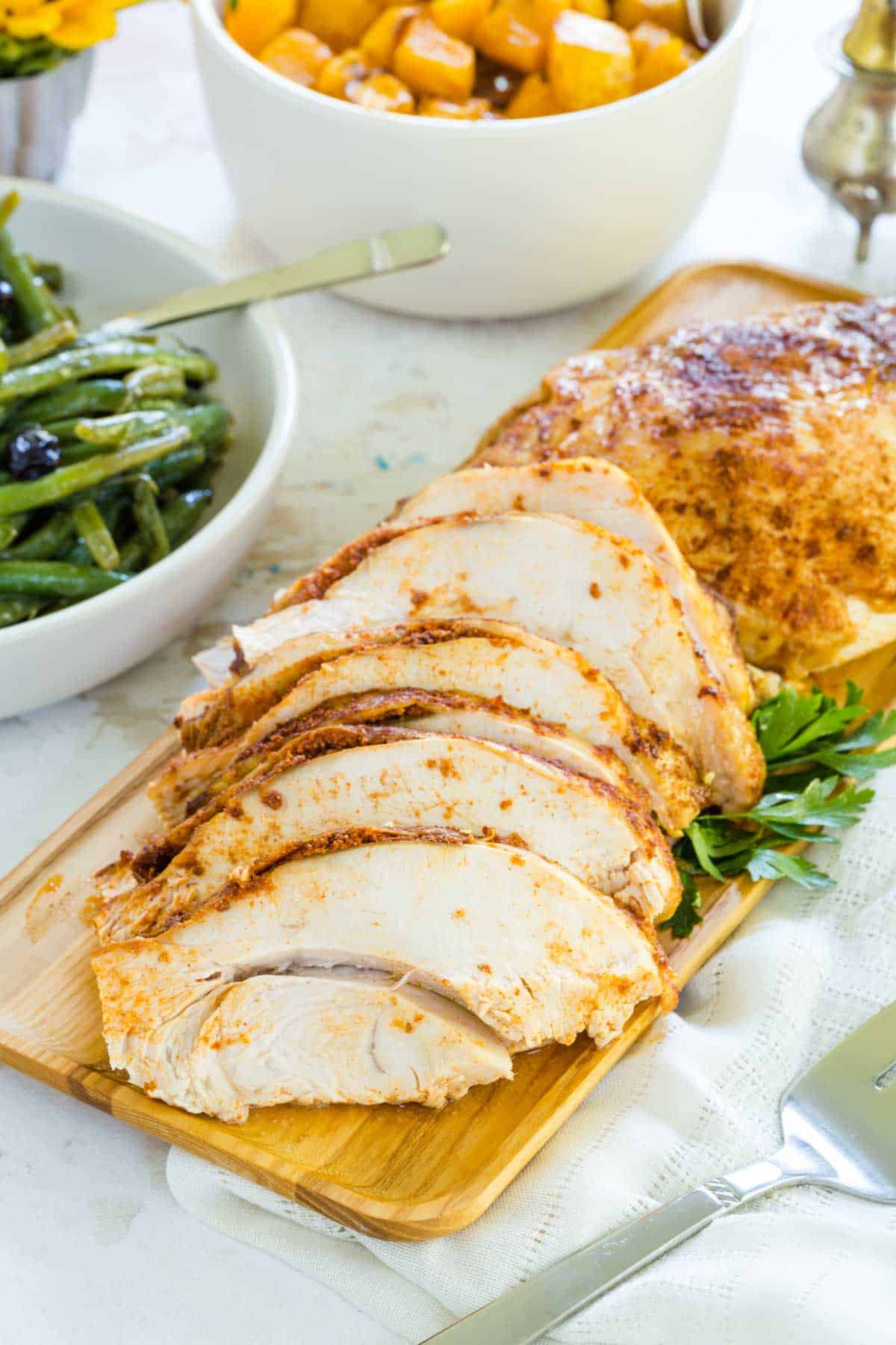 A seasoned turkey breast sliced up on a cutting board.