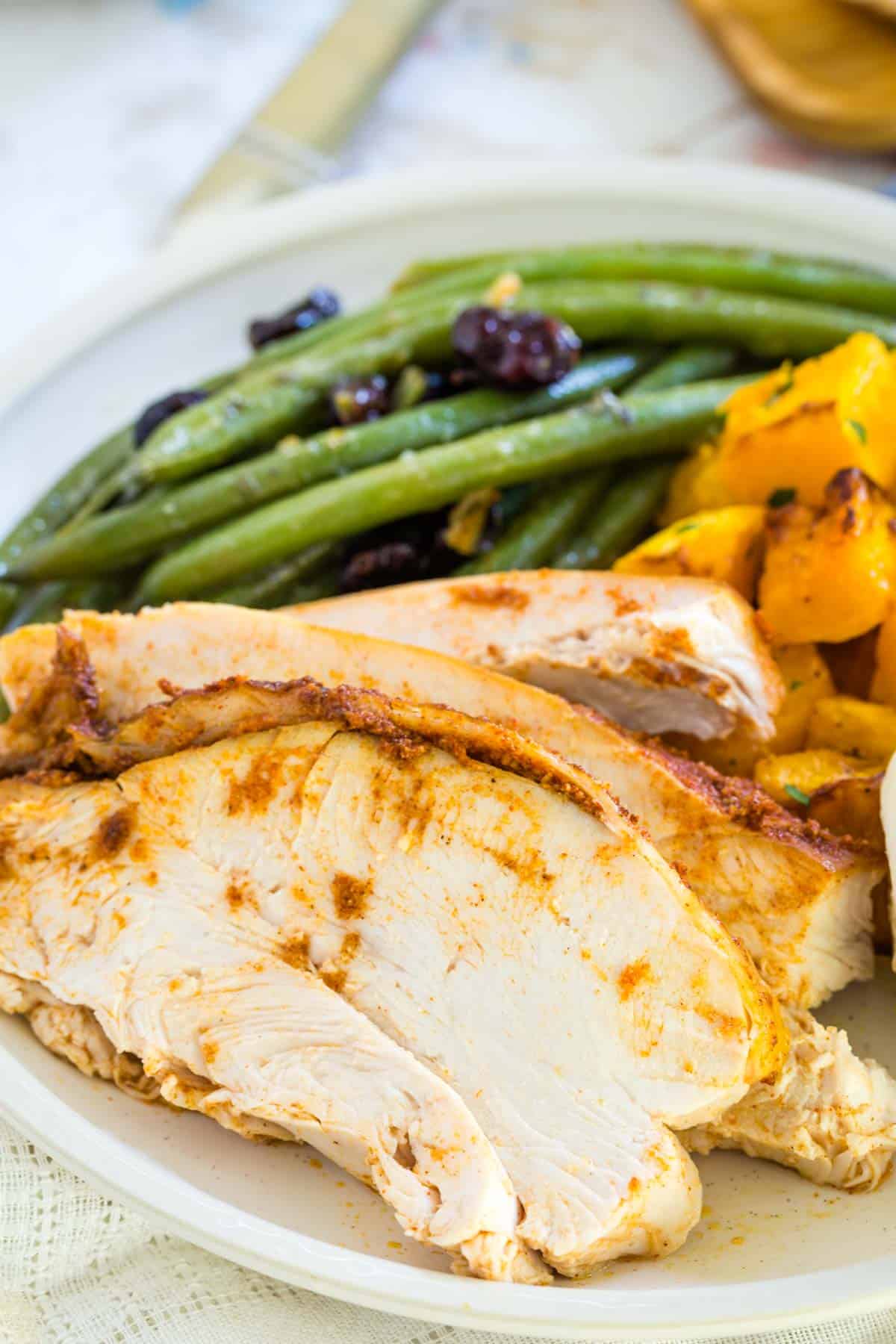 Turkey, green beans and roasted squash on a plate.