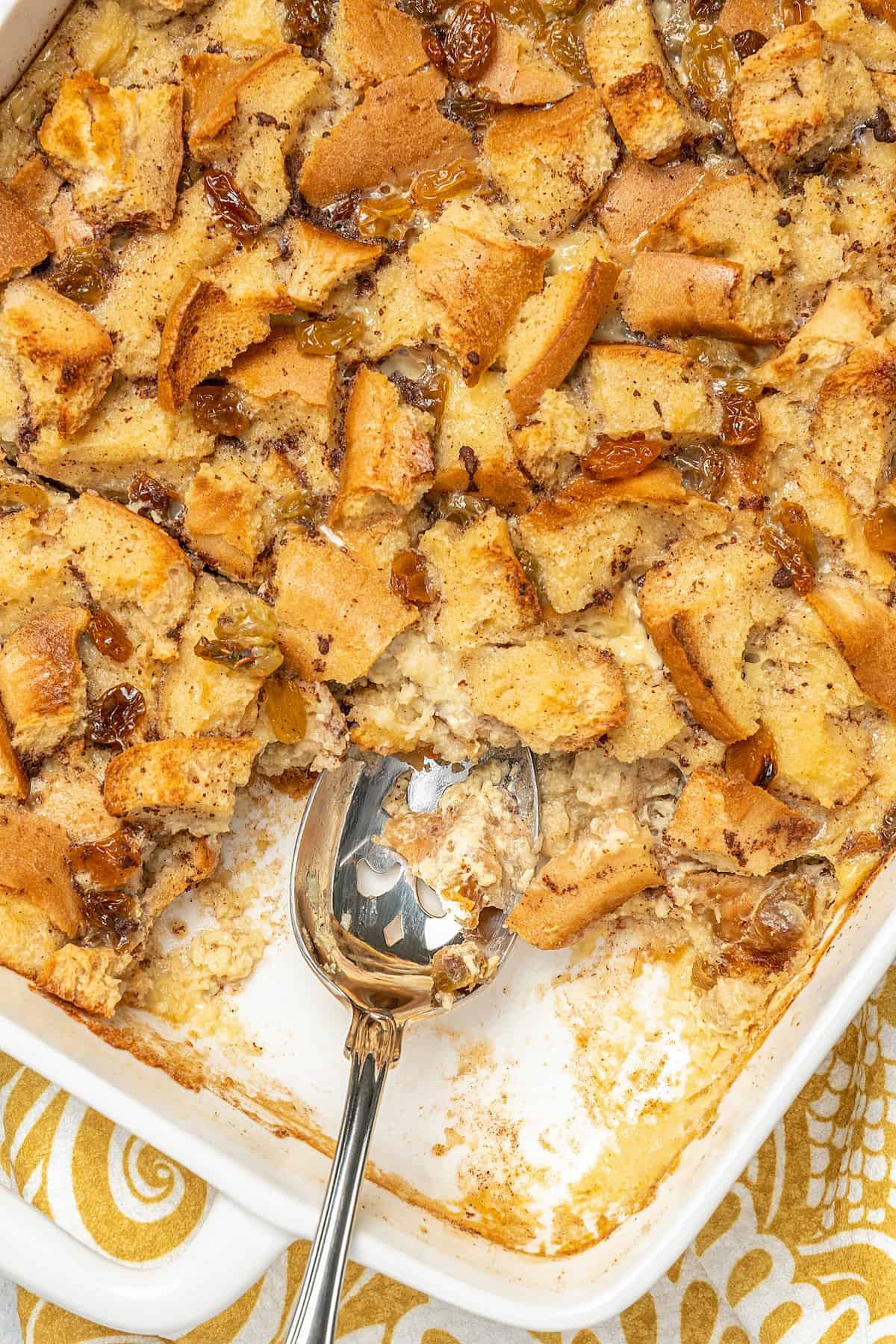 Close up of gluten-free bread pudding in a baking dish with a serving missing.