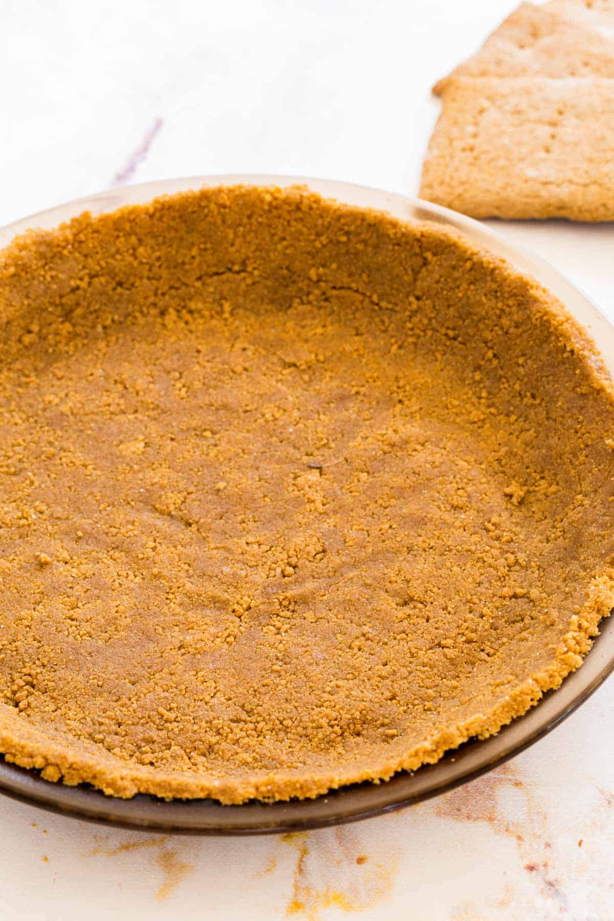 Gluten-free graham cracker crust pressed into a metal pie plate.