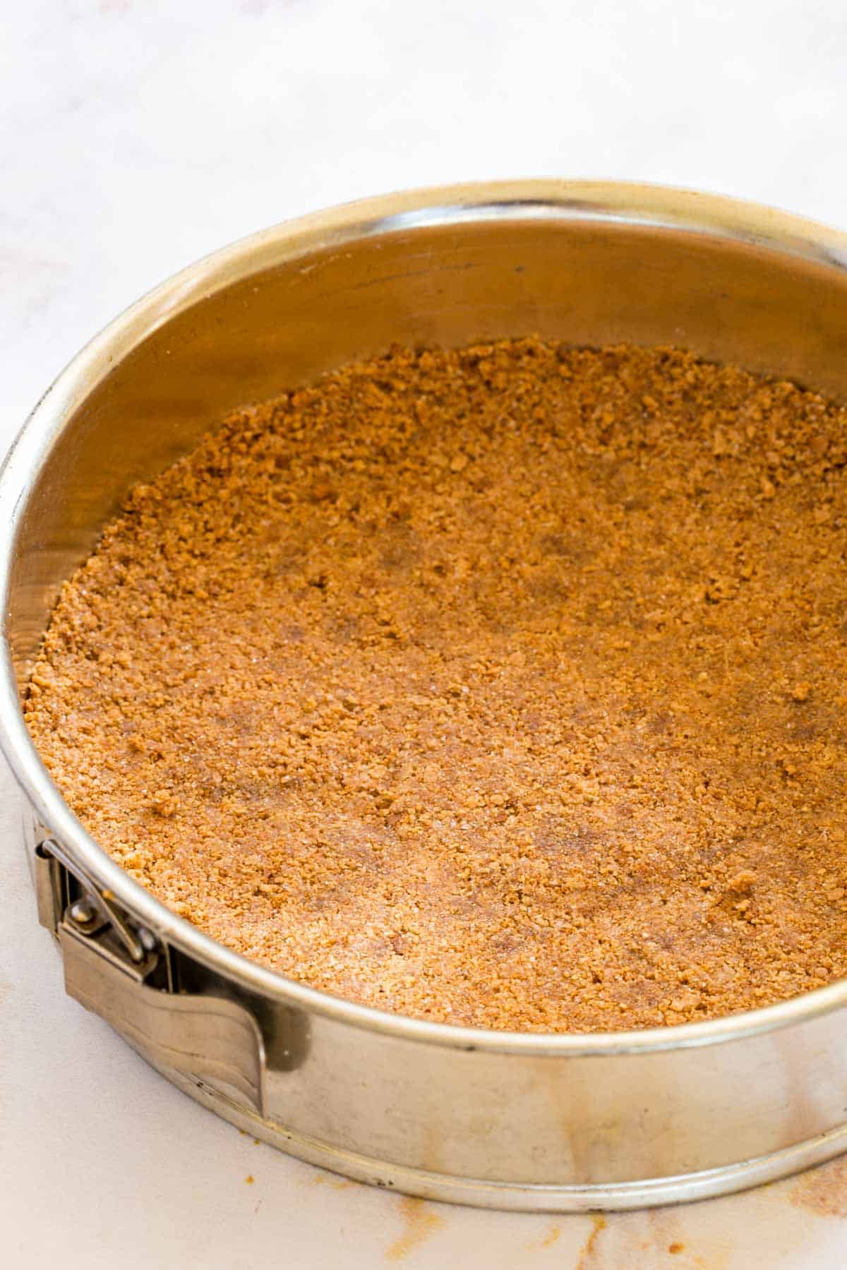 Gluten-free graham cracker crust pressed into a springform pan.