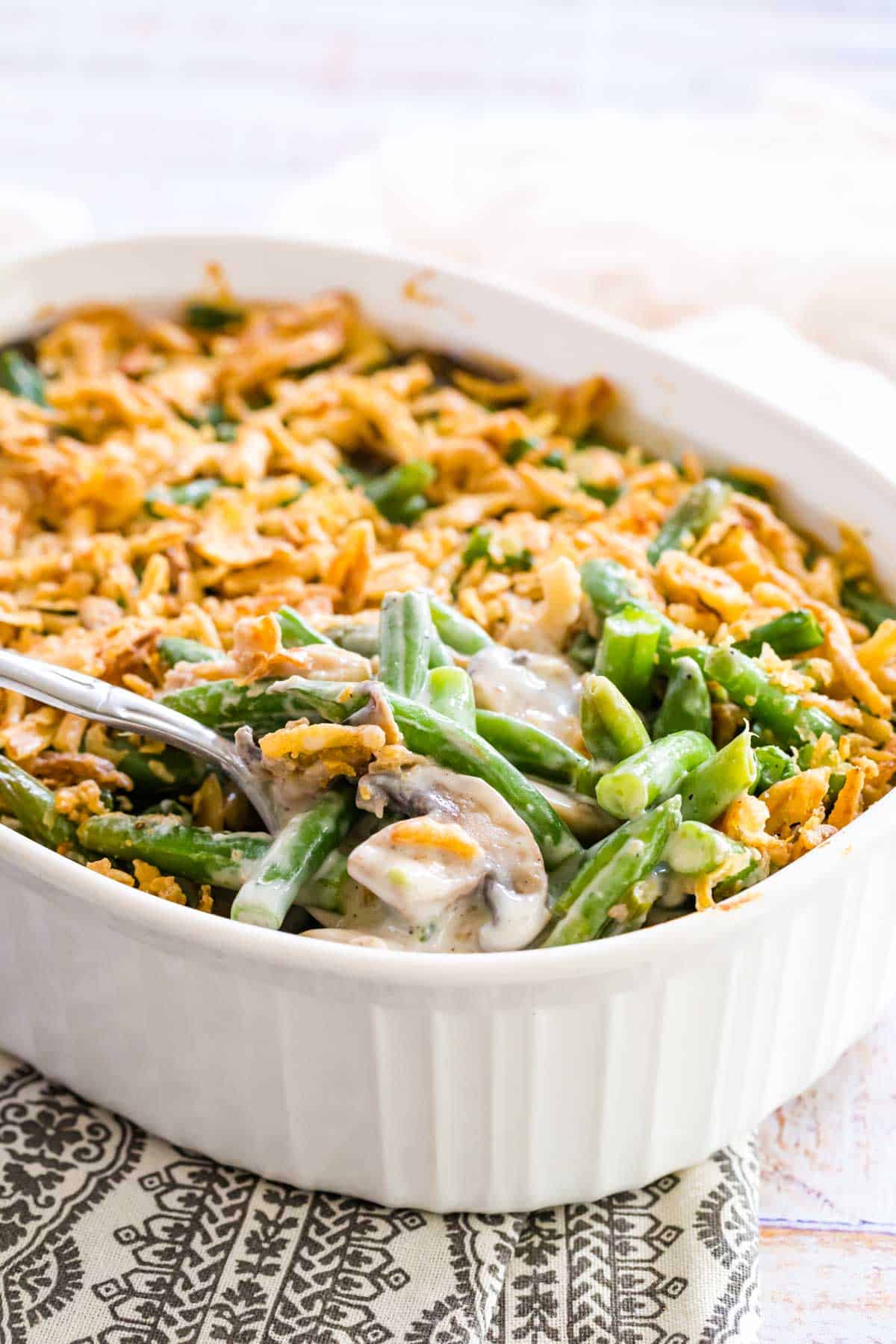 Gluten-free green bean casserole in a large white baking dish with a serving spoon.