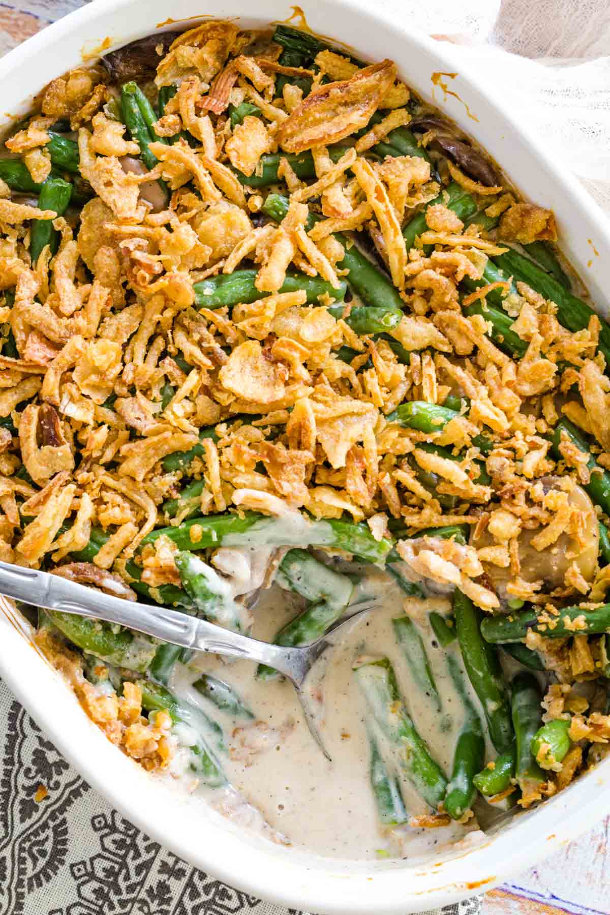 Overhead view of a gluten-free green bean casserole in a baking dish with a corner serving missing.