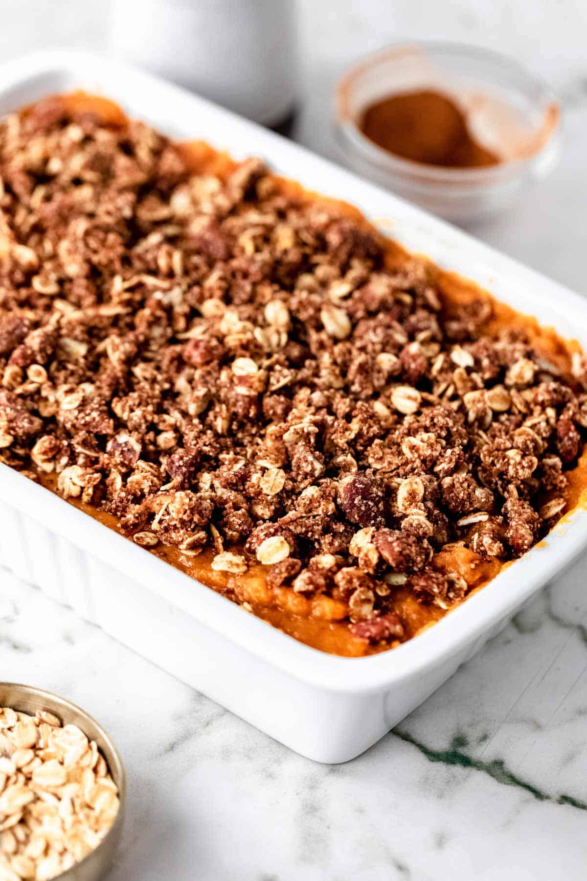 Sweet potato casserole topped with a pecan oat crumble in a rectangular baking dish.