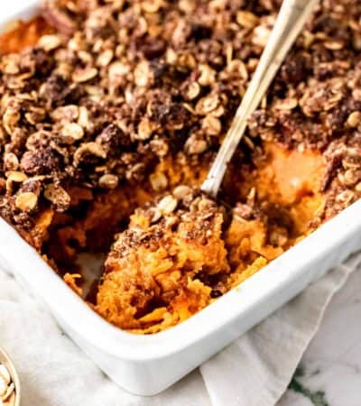 Overhead view of sweet potato casserole in a baking dish with a large serving spoon.