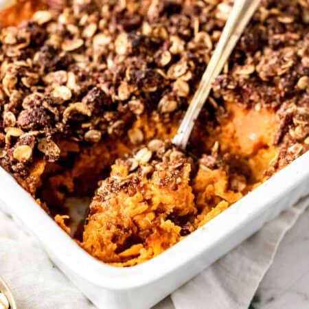 Overhead view of sweet potato casserole in a baking dish with a large serving spoon.