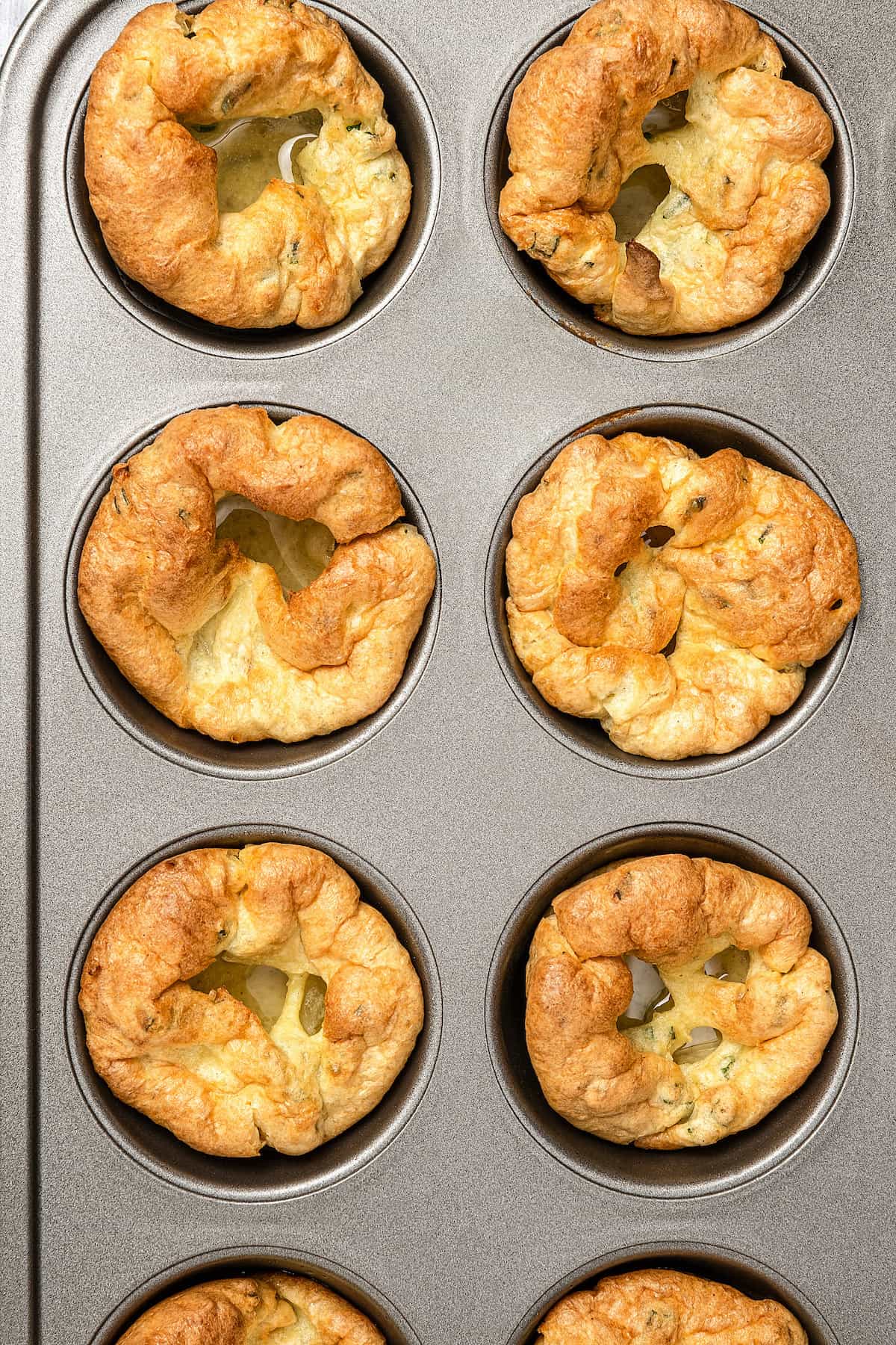 Overhead close up of baked gluten-free Yorkshire puddings in a muffin tin.