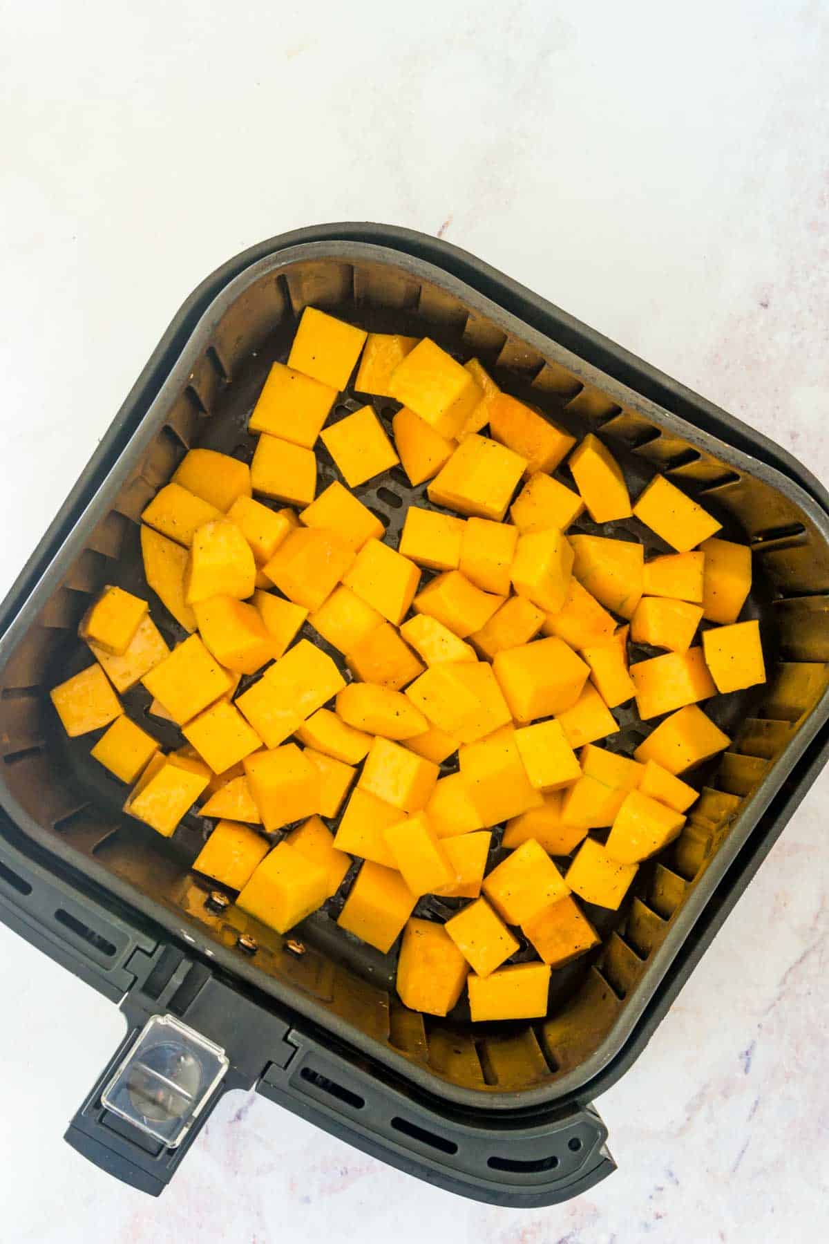 Cubed butternut squash inside an air fryer.