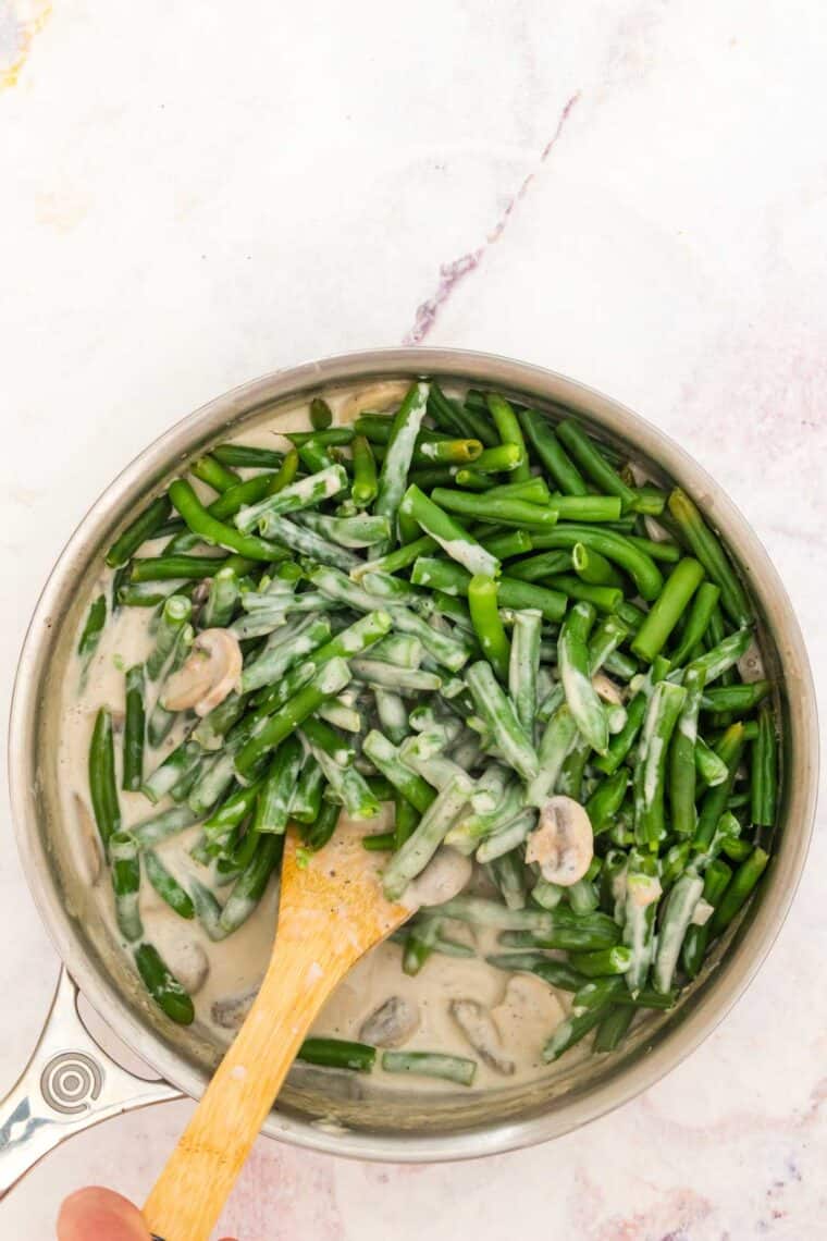 Green beans are added into a skillet with the mushroom cream sauce.