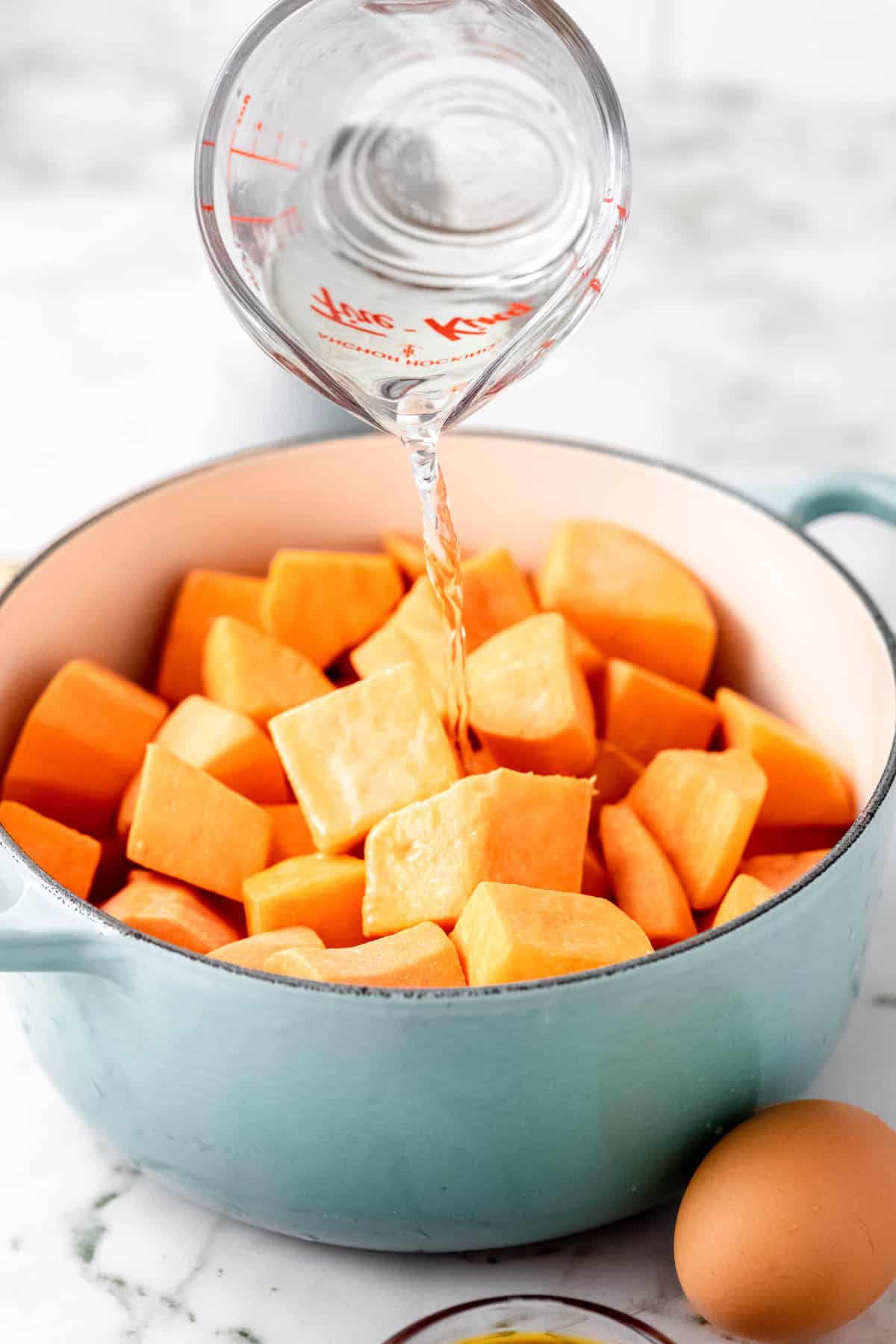 Water is poured into a pot filled with chopped sweet potatoes.