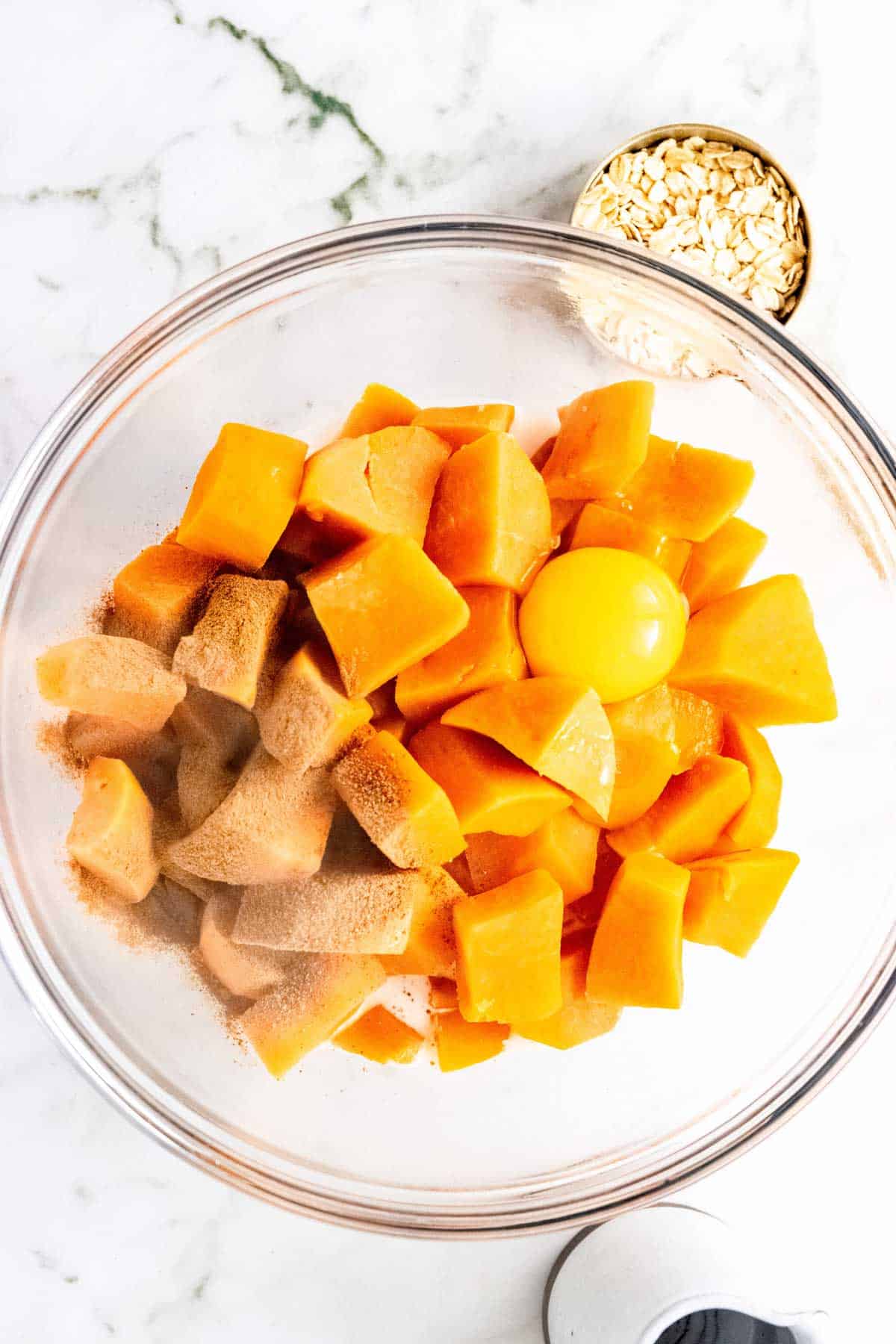 Cooked sweet potato chunks combined with spices in a glass bowl.