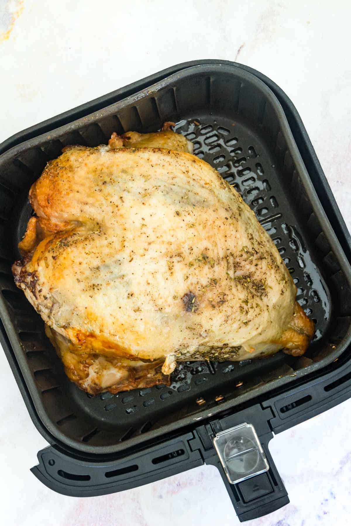 Roast turkey breast inside the basket of an air fryer.
