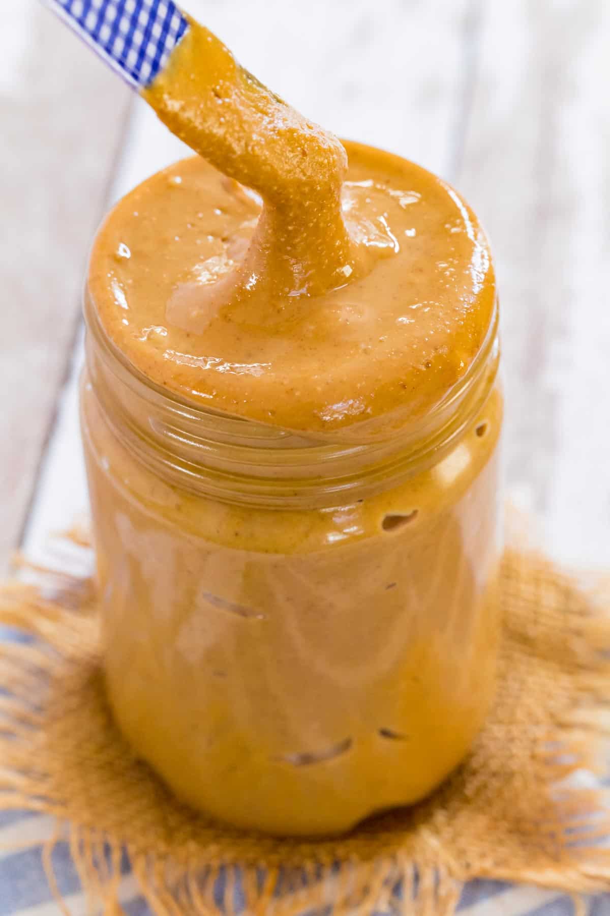 A knife being dipped into a jar of peanut butter.