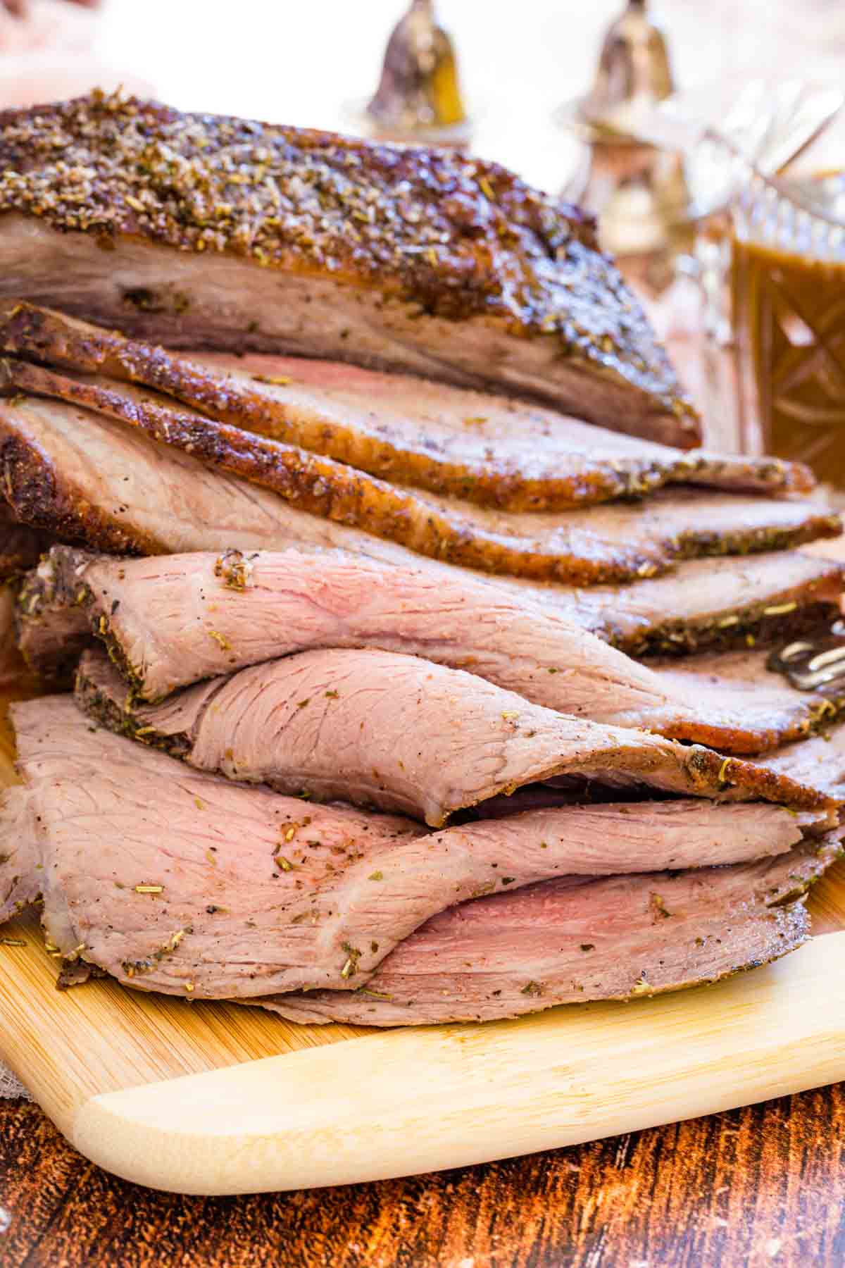 Cooked bottom round roast sliced up on a wooden cutting board.