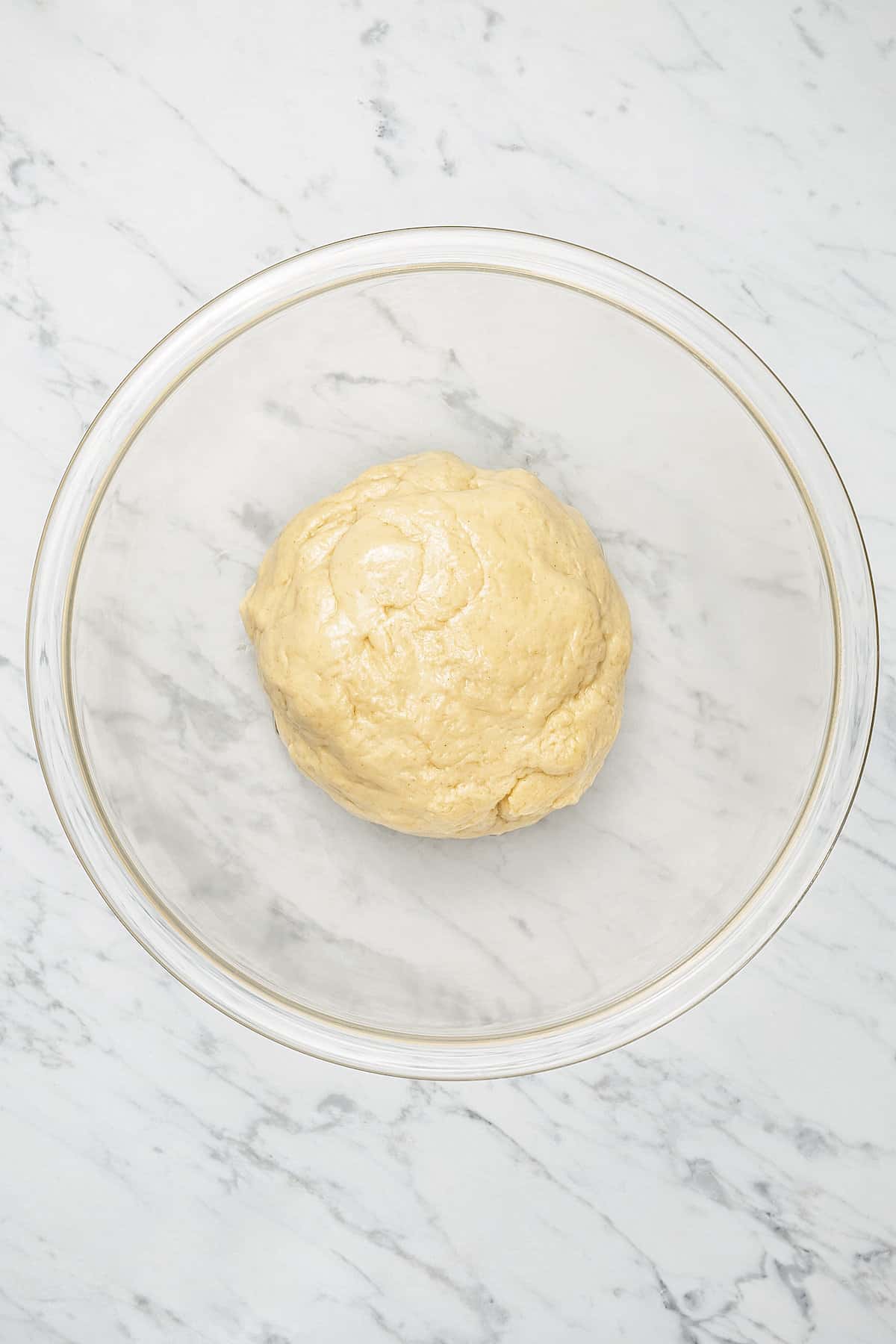 Honey bun dough in the bottom of a glass bowl.