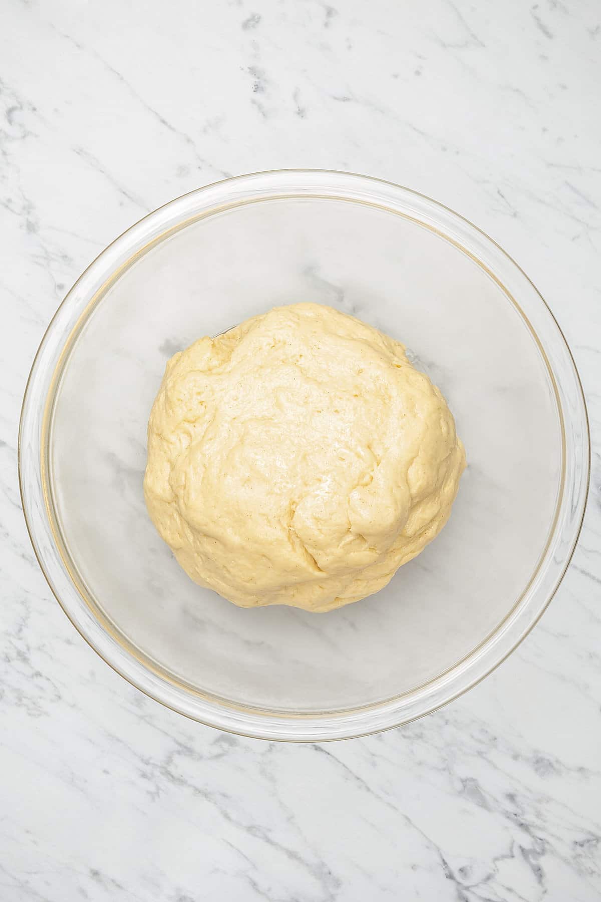Honey bun dough after rising in a glass bowl.