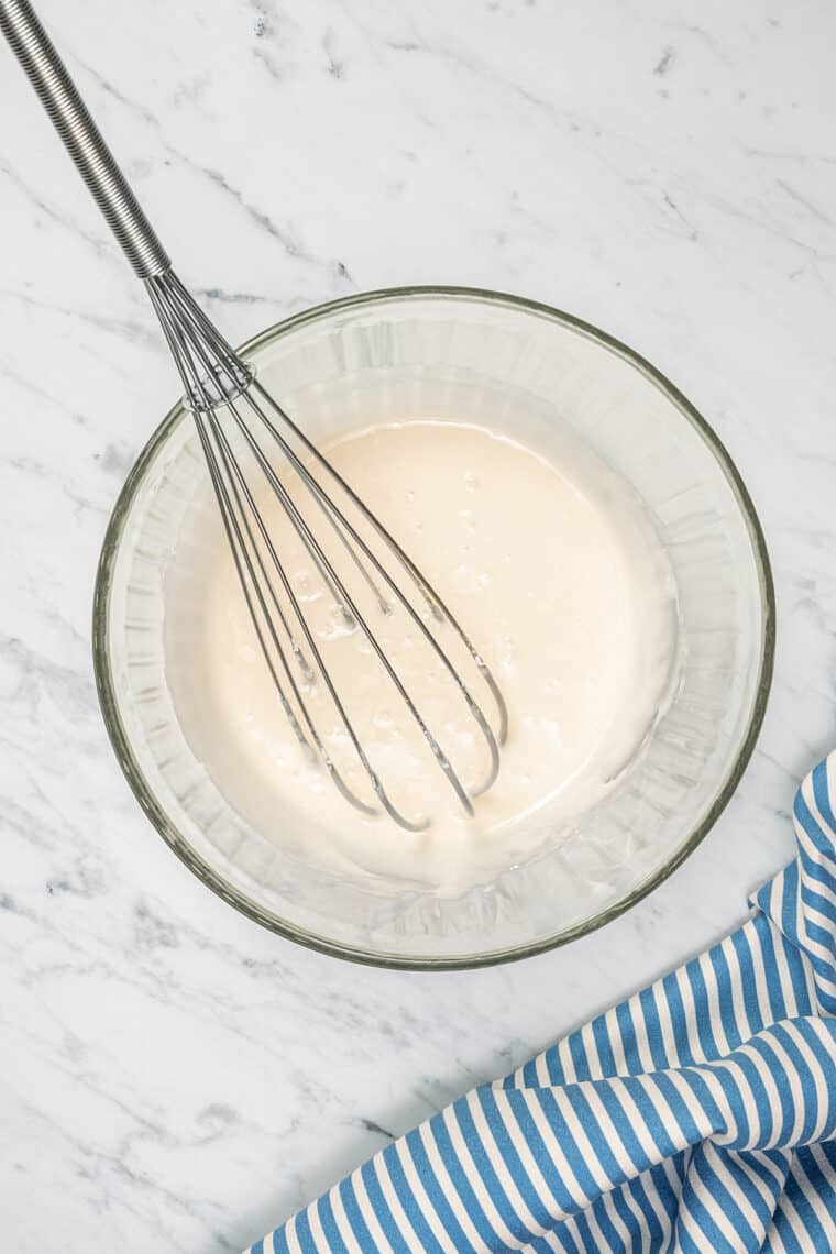 Vanilla glaze in a mixing bowl with a whisk.