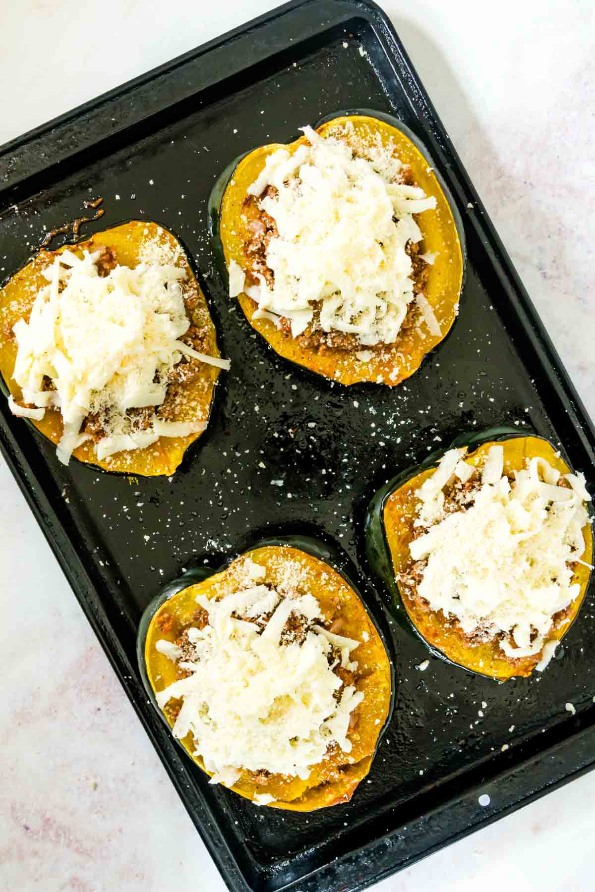 Lasagna stuffed acorn squash on a baking sheet ready to go into the oven.