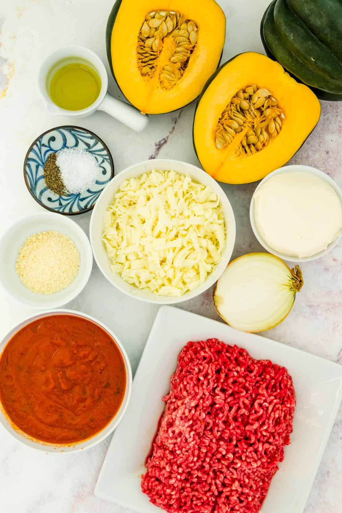 The ingredients to make stuffed acorn squash on a marble tabletop.