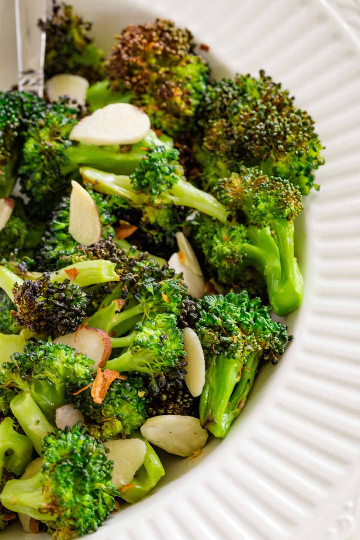 Air fryer broccoli in a bowl topped with almond slices.