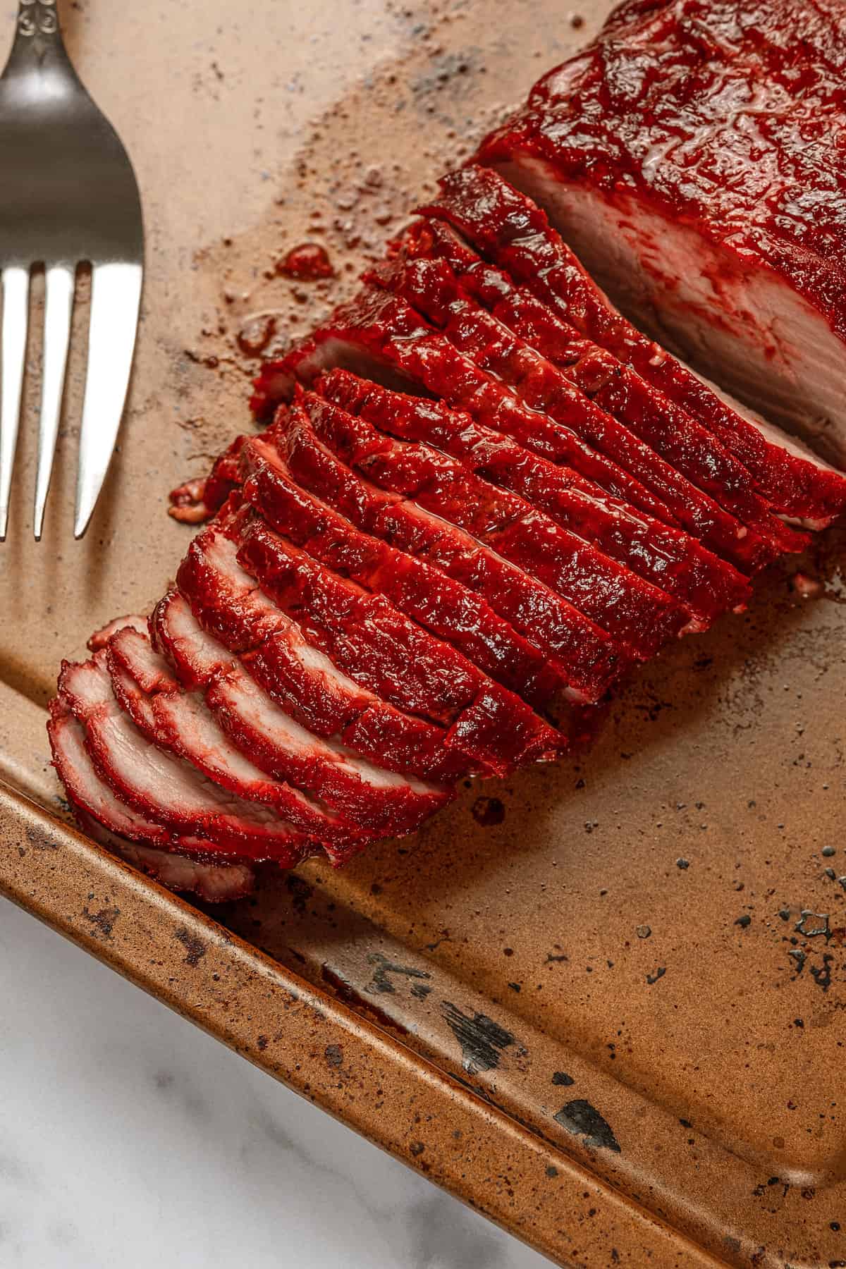 Char siu pork loin sliced thinly on a wooden cutting board.