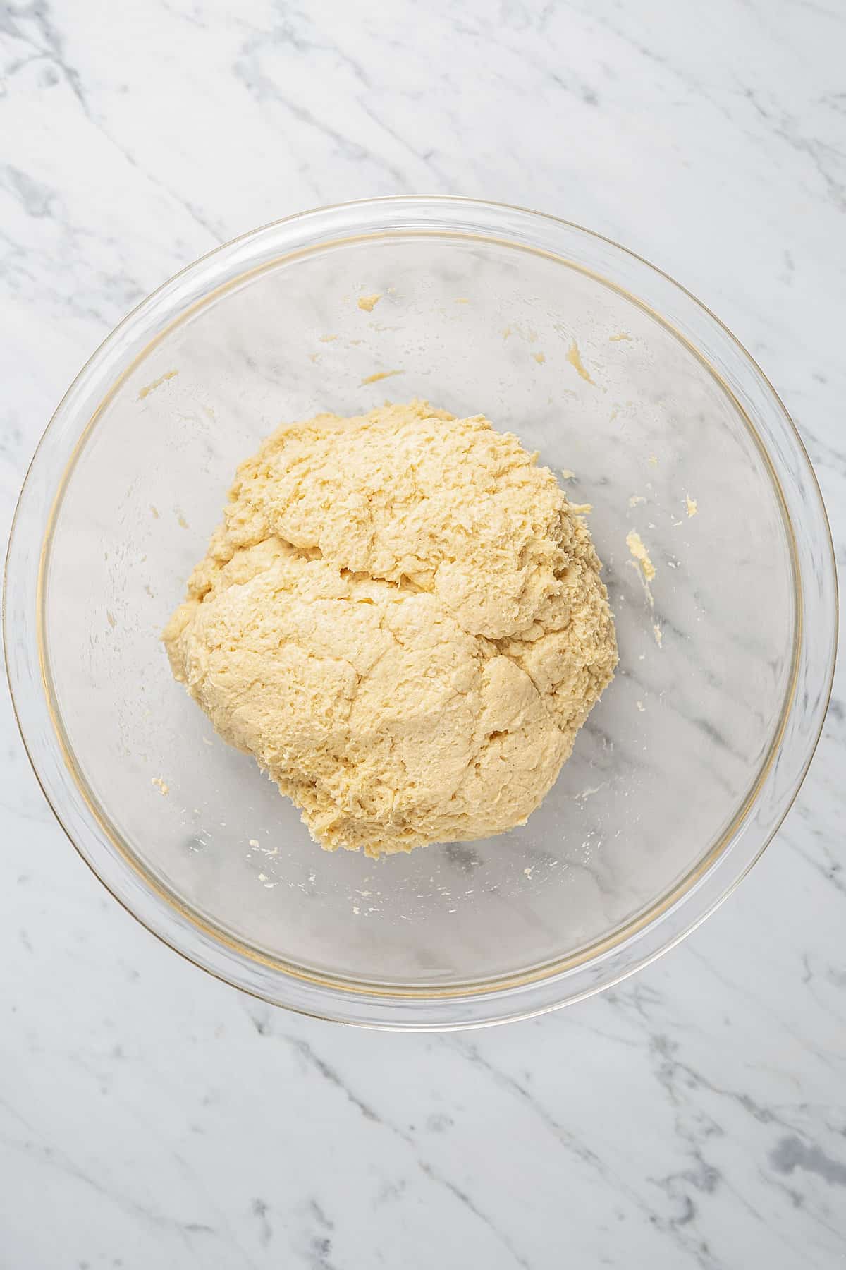 The dough for gluten-free bread bowls in the bottom of a glass mixing bowl.