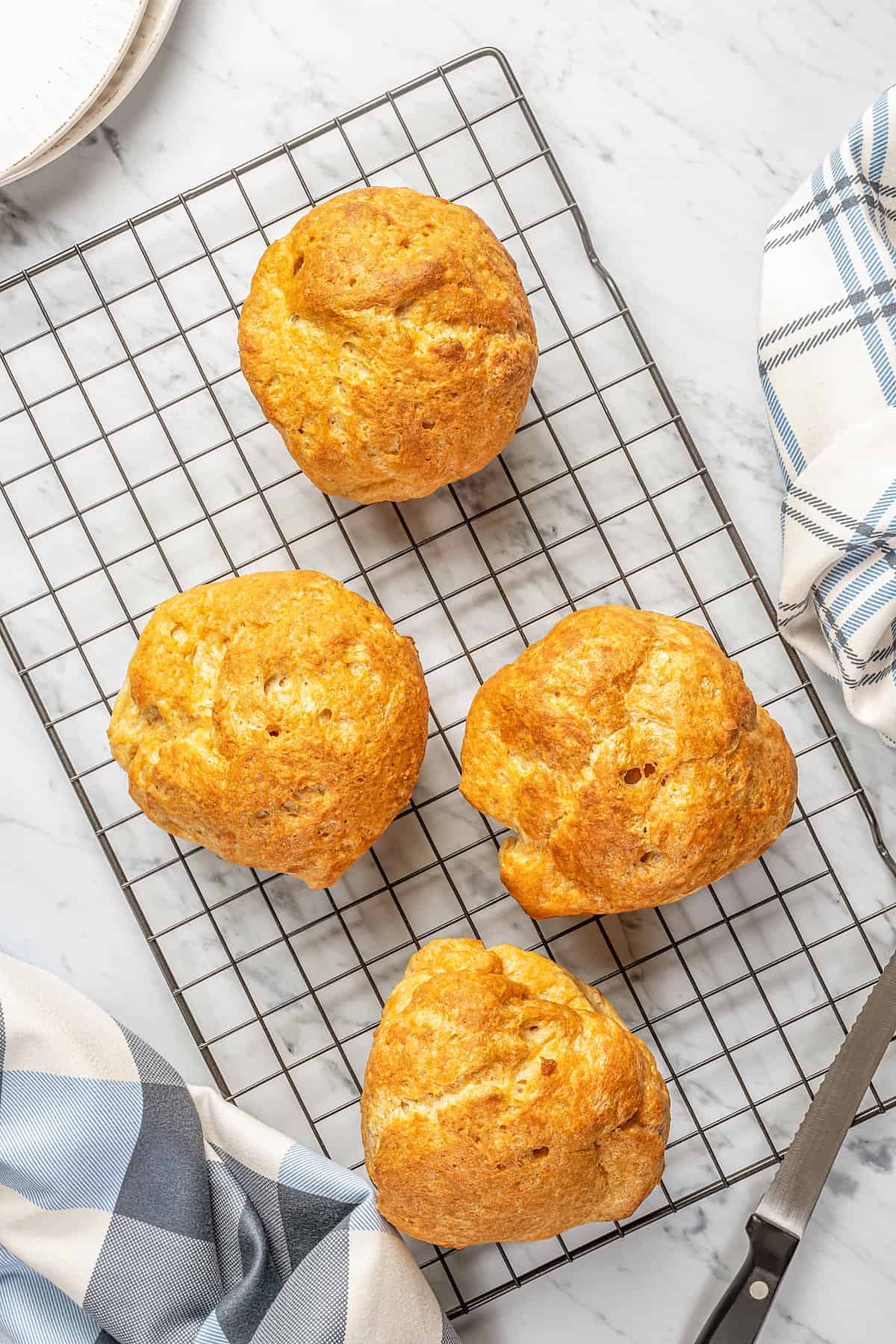 Four round loaves of gluten-free bread on a wire rack.