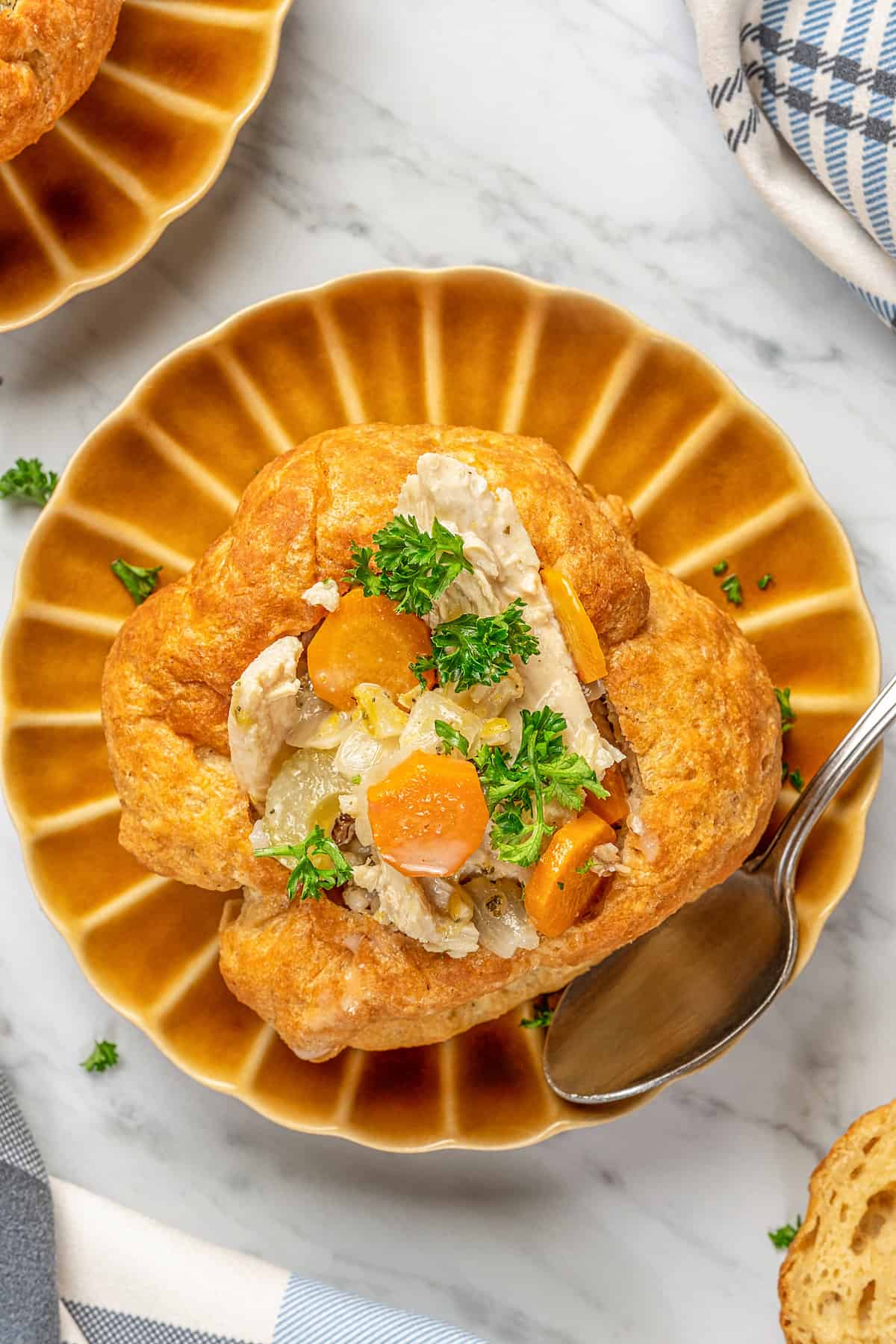 Overhead close up of a gluten-free bread bowl on brown plates, filled with chicken and vegetables.