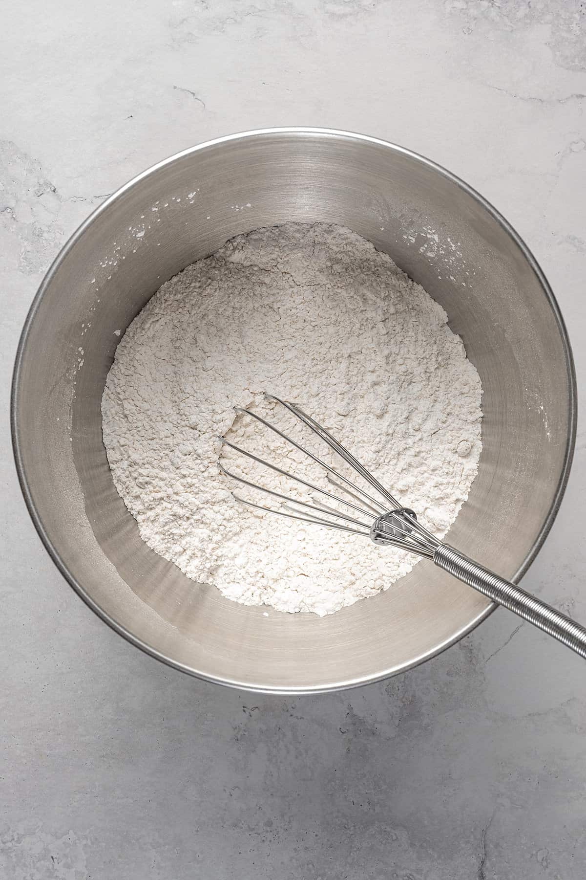 Dry ingredients whisked together in a metal mixing bowl.
