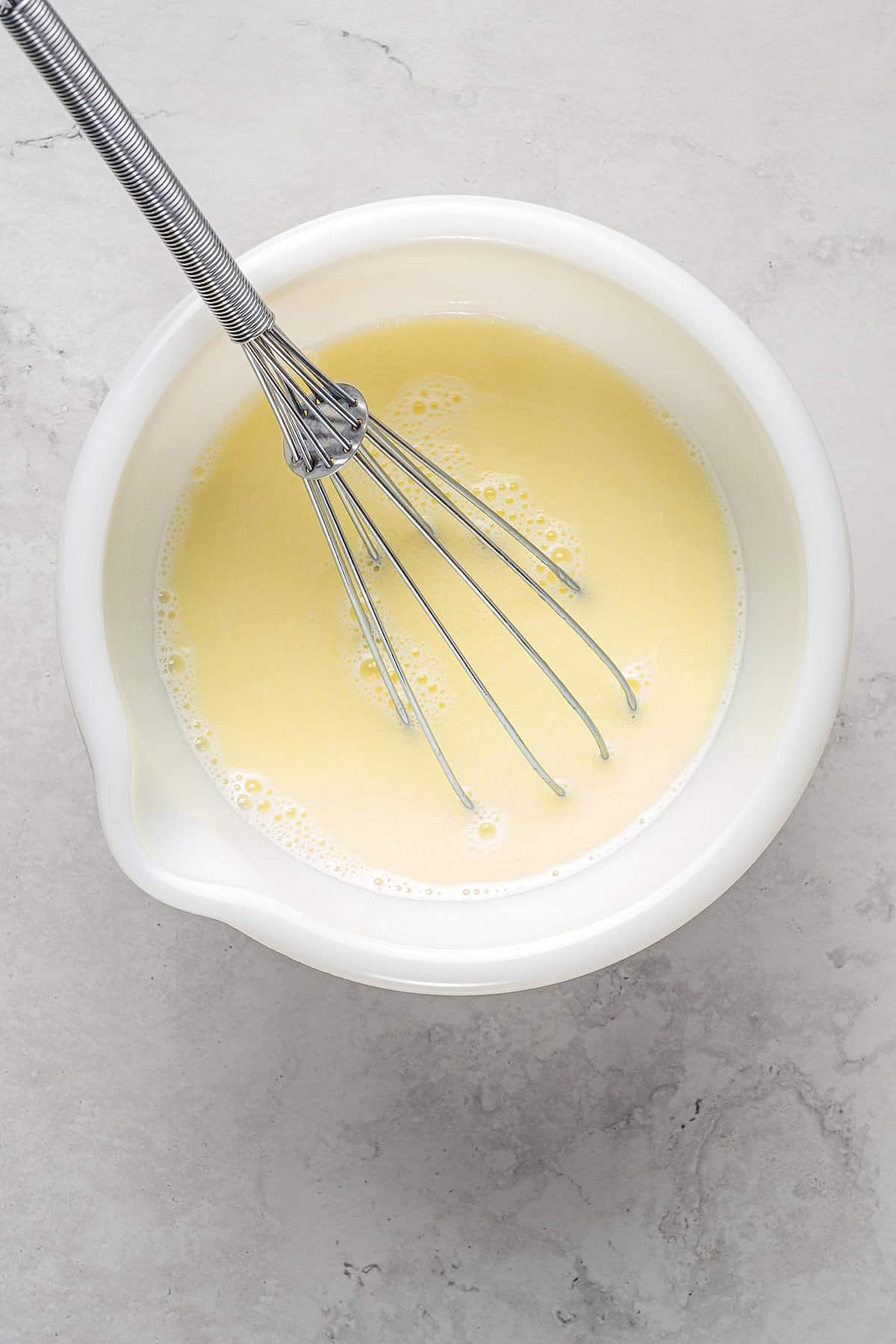 Milk and melted butter whisked together in a plastic bowl.