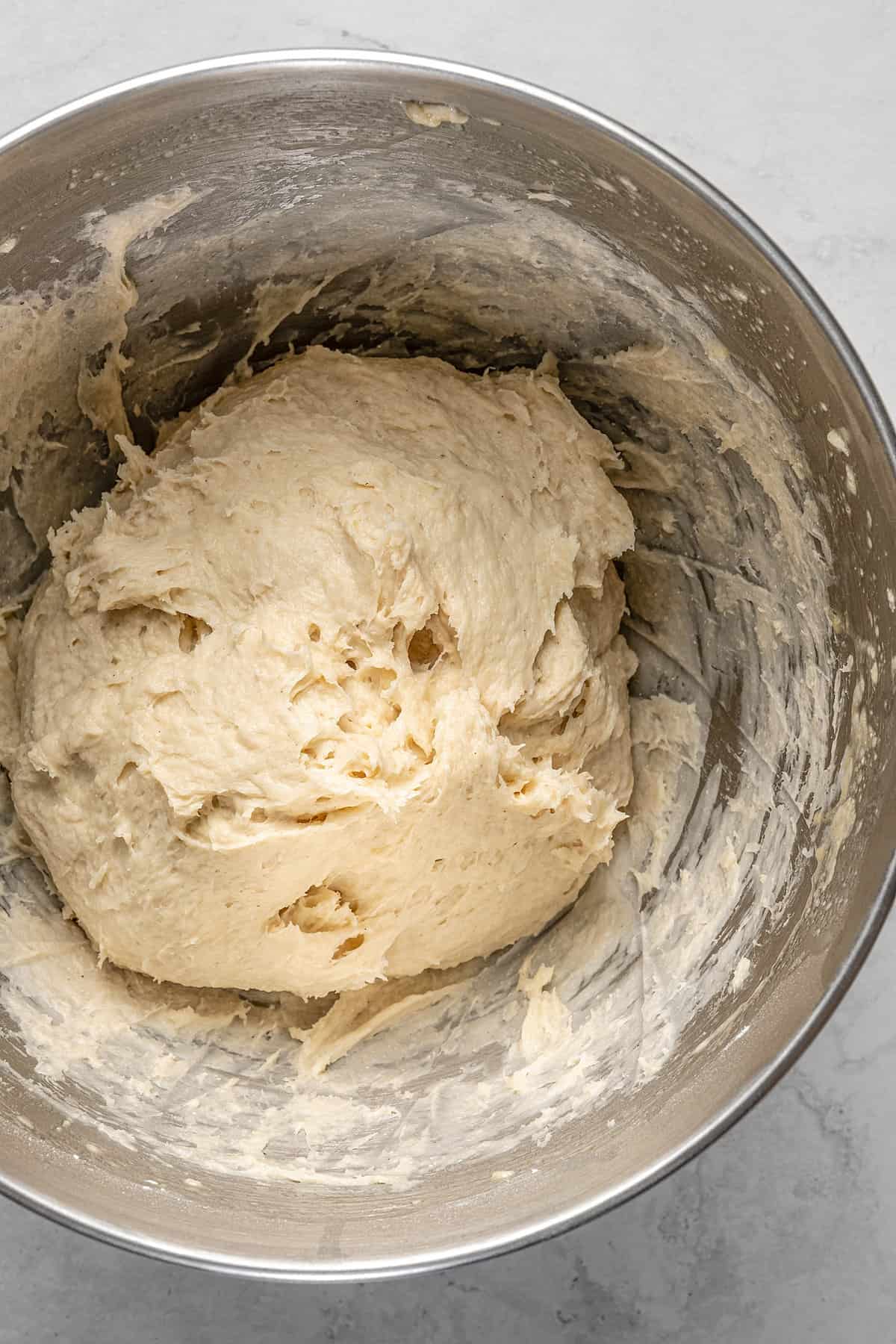 Dough for gluten-free Hawaiian rolls in the bottom of a metal mixing bowl.