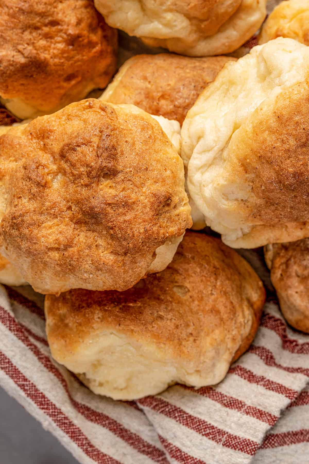 Close up of gluten-free Hawaiian rolls piled in a cloth-lined bowl.