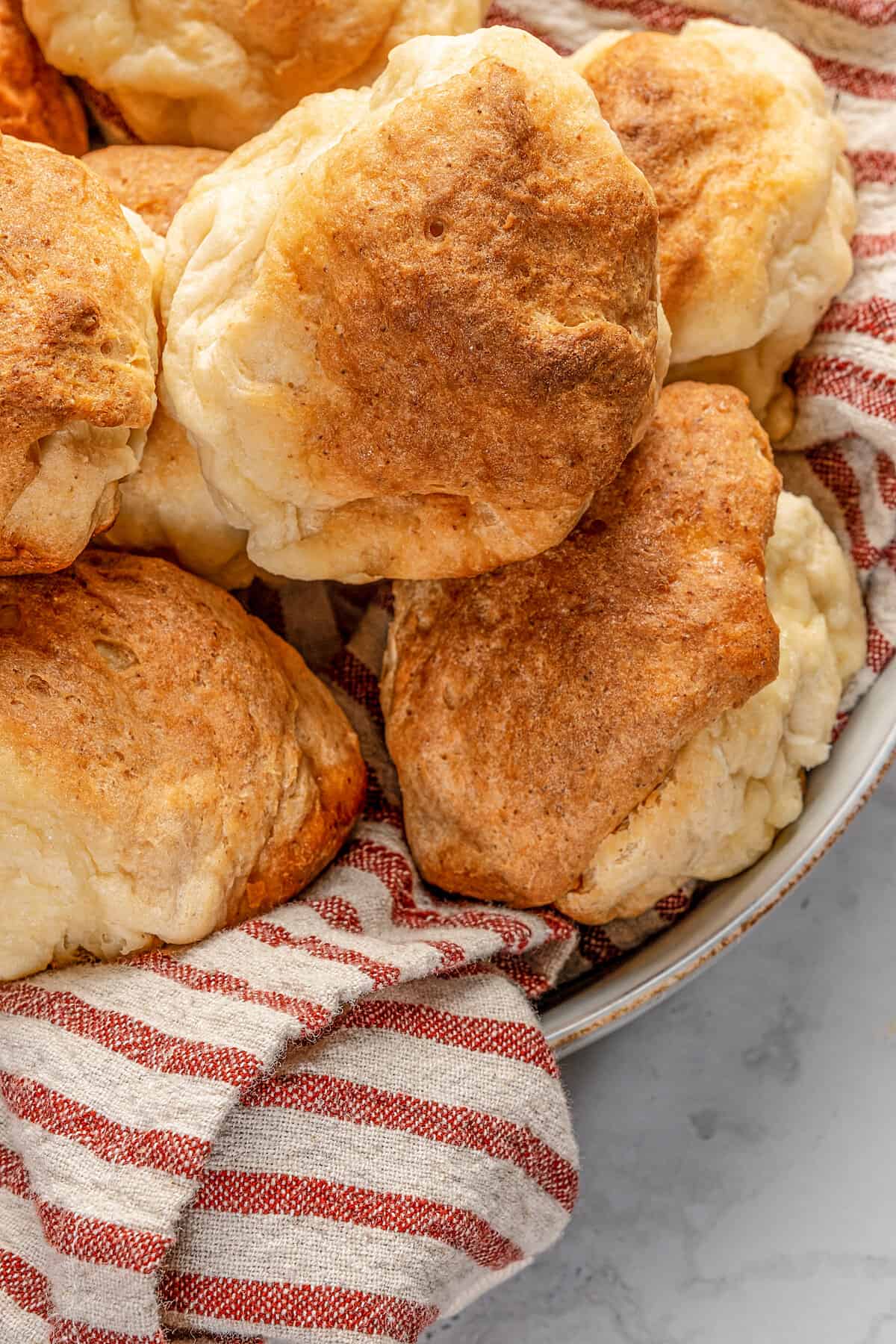 Close up of gluten-free Hawaiian rolls piled in a cloth-lined bowl.