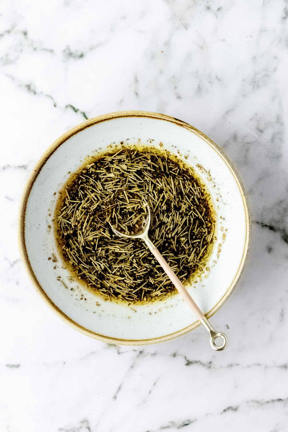 A bowl of rosemary balsamic marinade with a spoon.