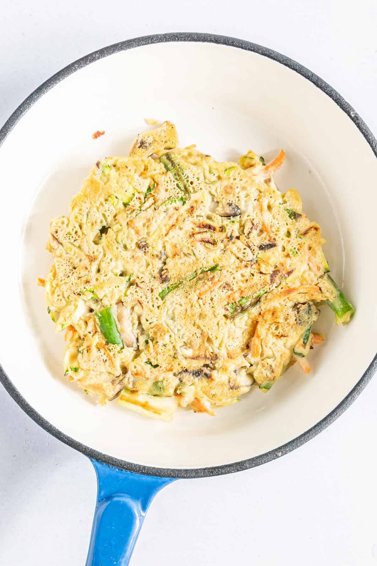 Vegetable pancake batter frying in a skillet.