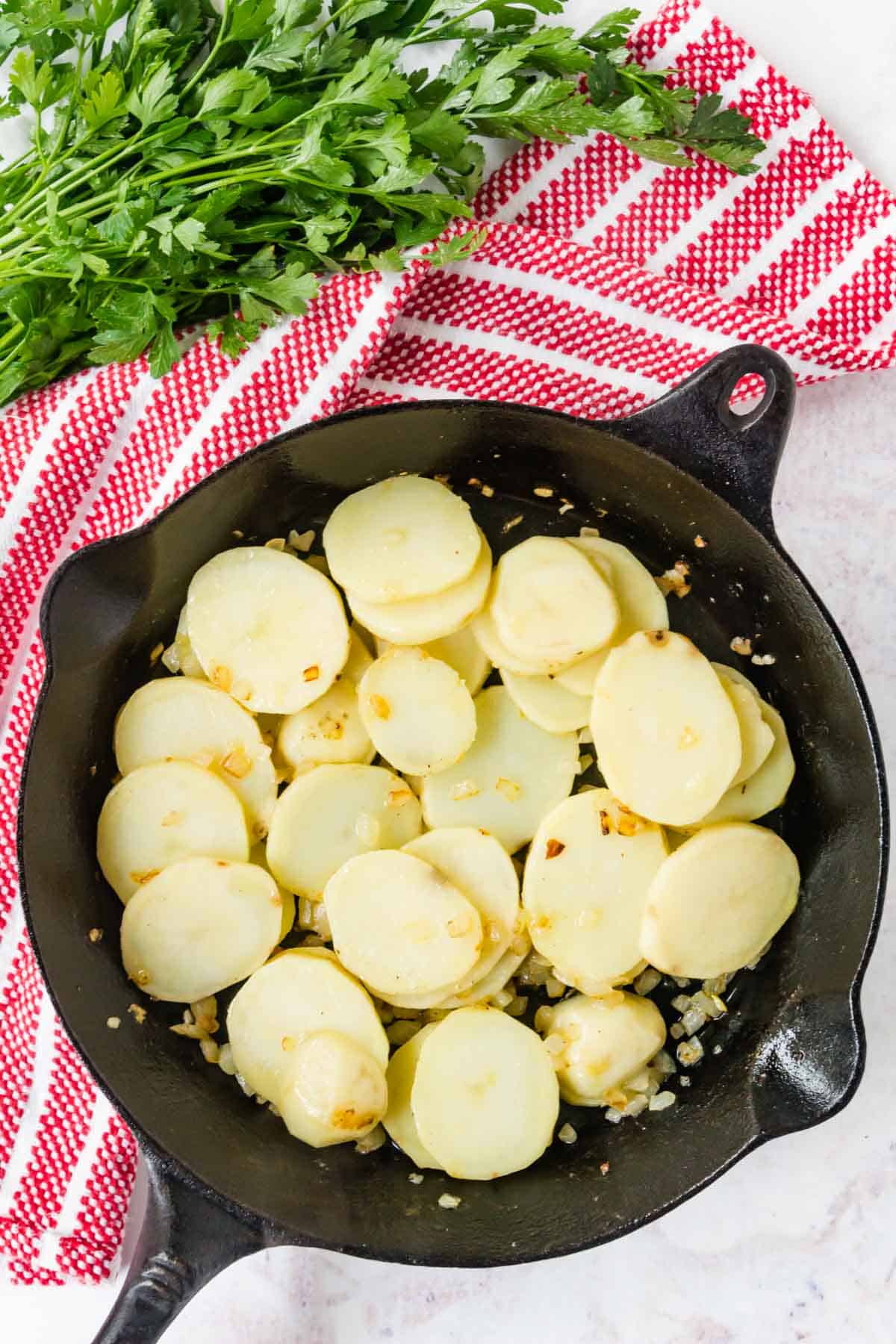 Sauteed sliced potatoes and chopped onions in a cast iron pan.