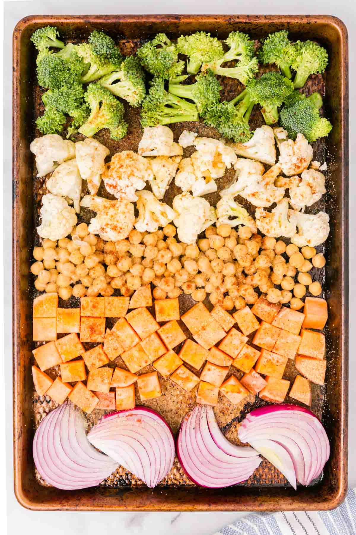 Assorted seasoned veggies ready for roasting on a sheet pan.