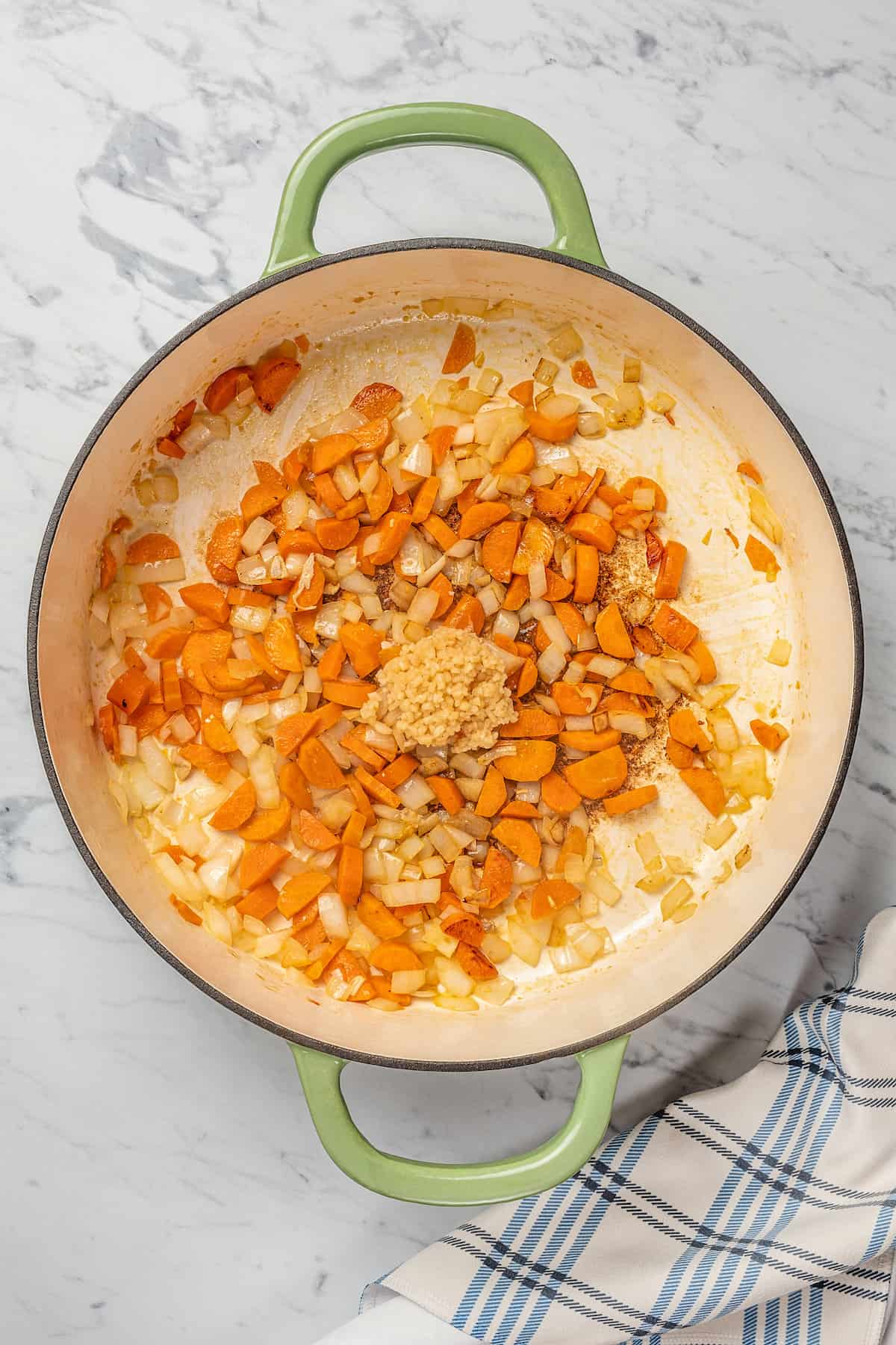 Minced garlic added to a pot with sautéd carrots and onions.