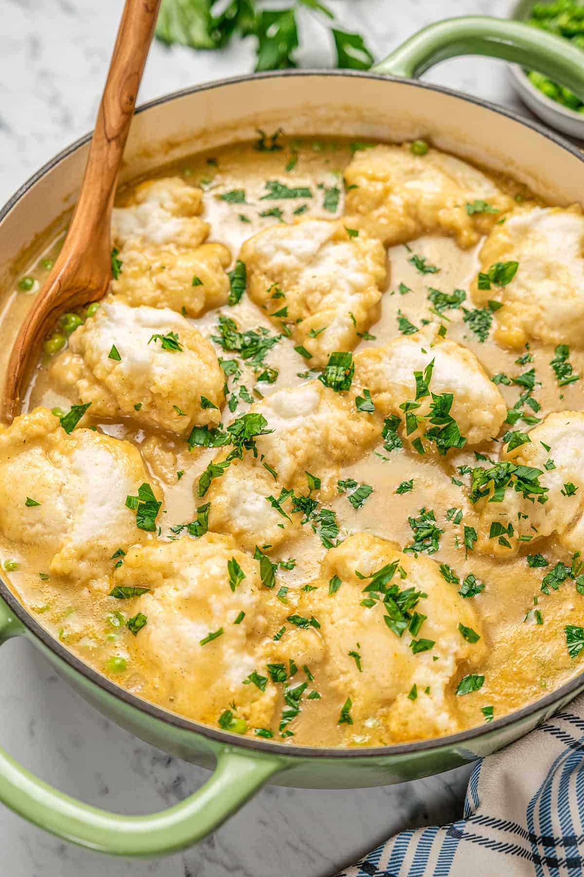 Gluten-free chicken and dumpling soup inside a large pot, garnished with fresh chopped parsley.