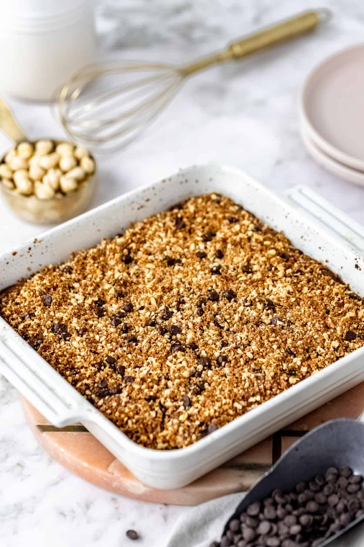 Baked gluten-free chocolate hazelnut crumb cake in a square baking dish on a marble countertop.