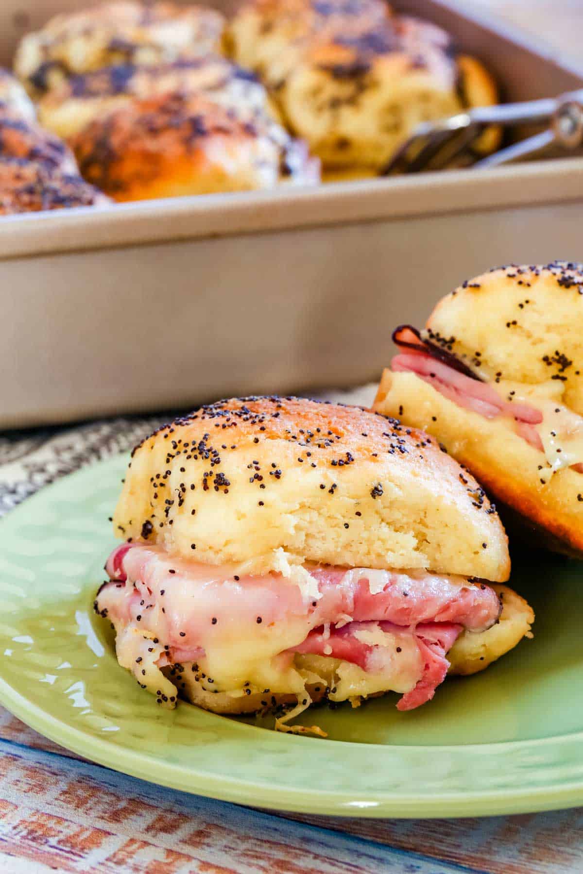 Two gluten-free ham and cheese sliders on a green plate.