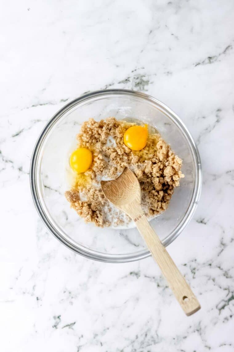 Eggs added to the crumb cake mixture in a glass mixing bowl.