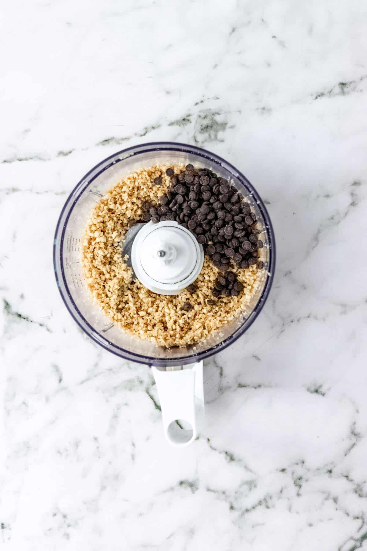 Chocolate chips added to the hazelnut crumb topping inside the food processor.