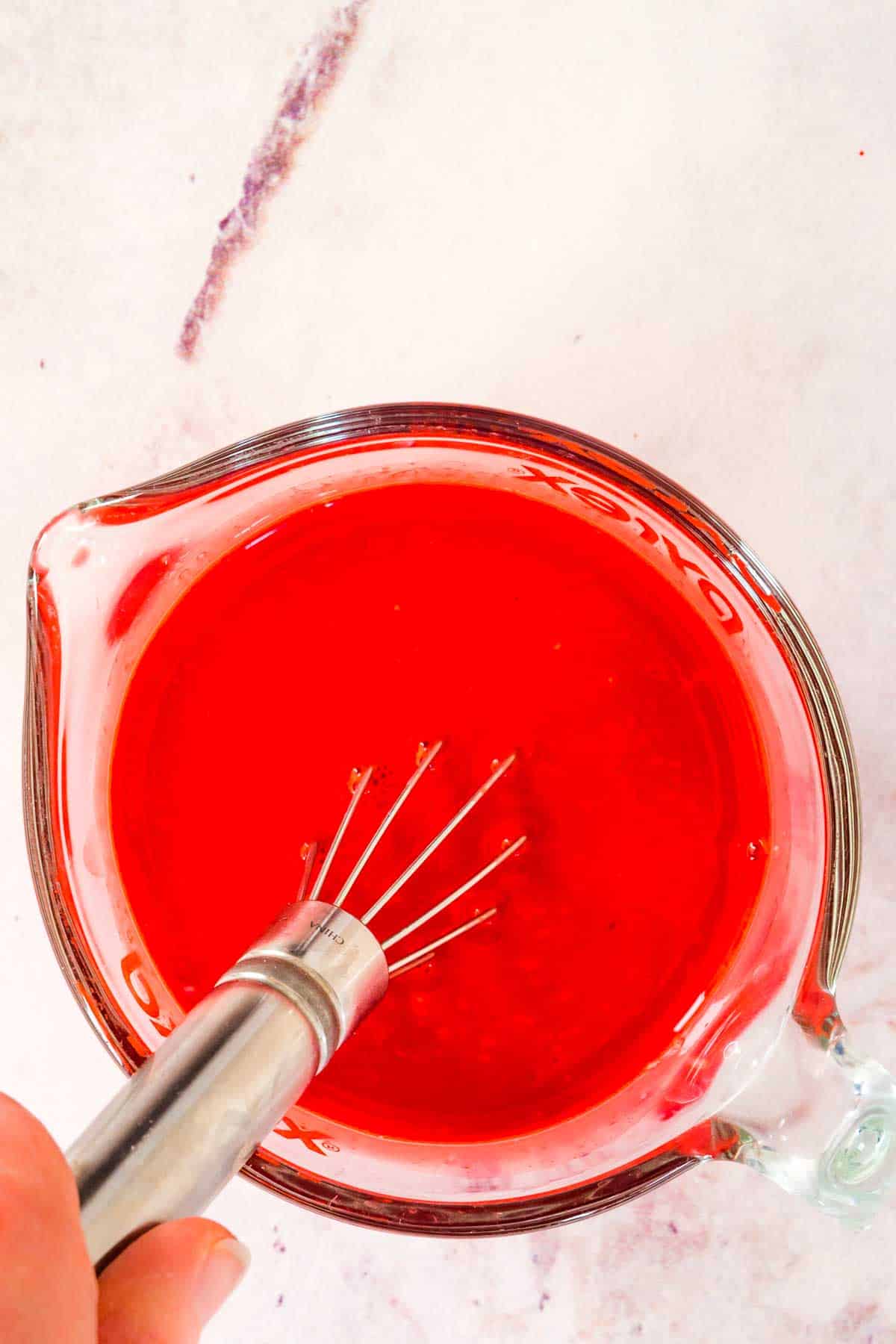 The red milk mixture for red velvet cake in a glass mixing bowl.