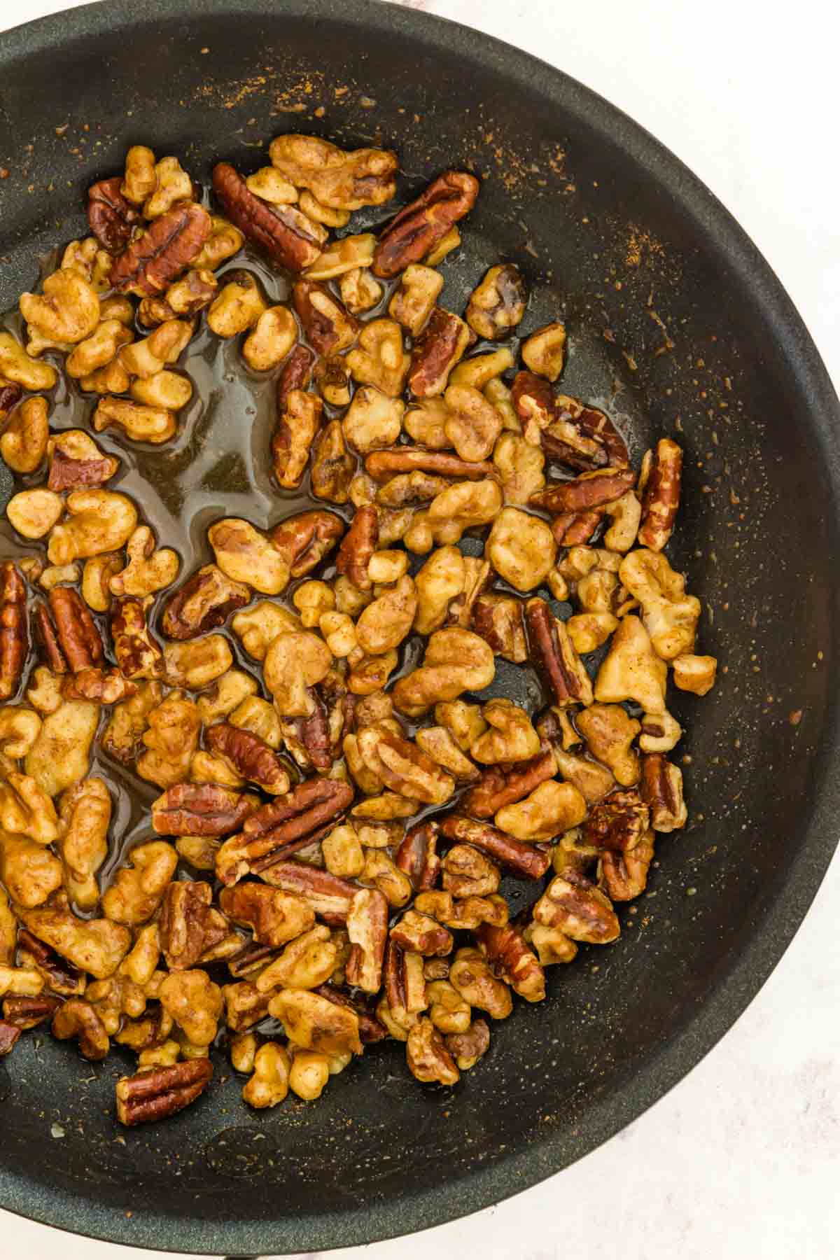 Honey glazed nuts in a skillet.