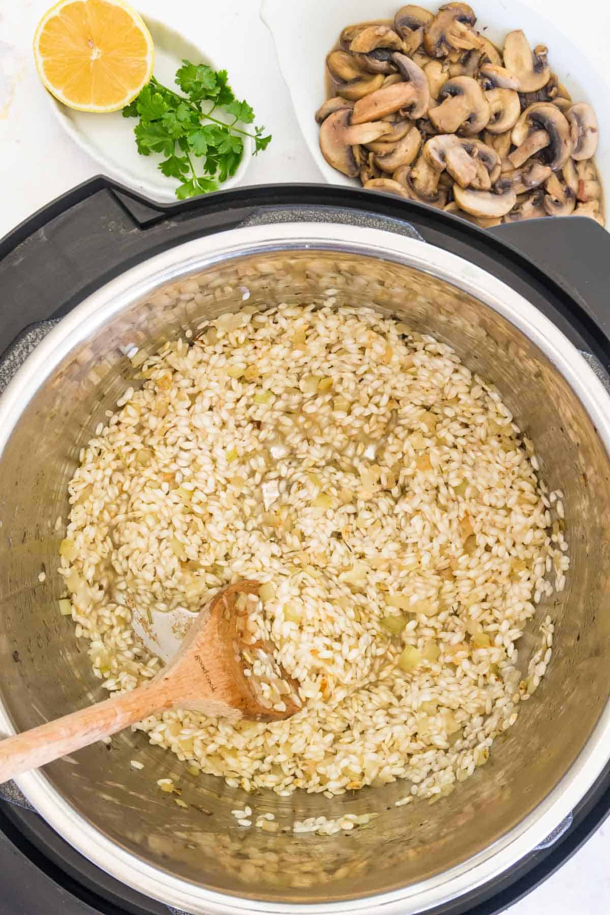 Softened arborio rice inside the Instant Pot with sauted onion and garlic.