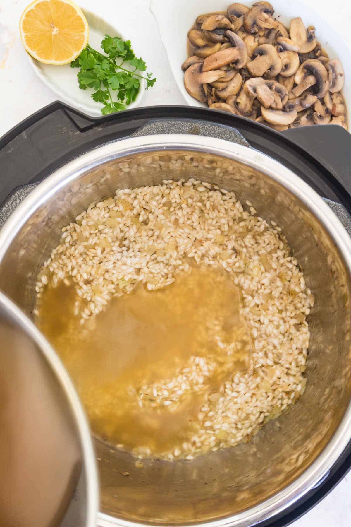 Chicken broth is added to risotto rice in the Instant Pot.