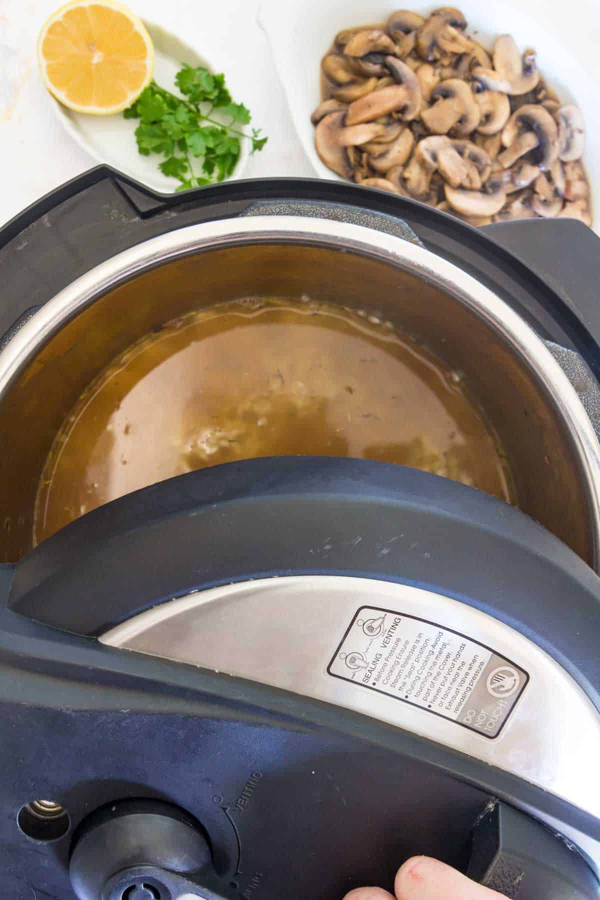 A lid is placed over the Instant Pot filled with risotto ingredients.
